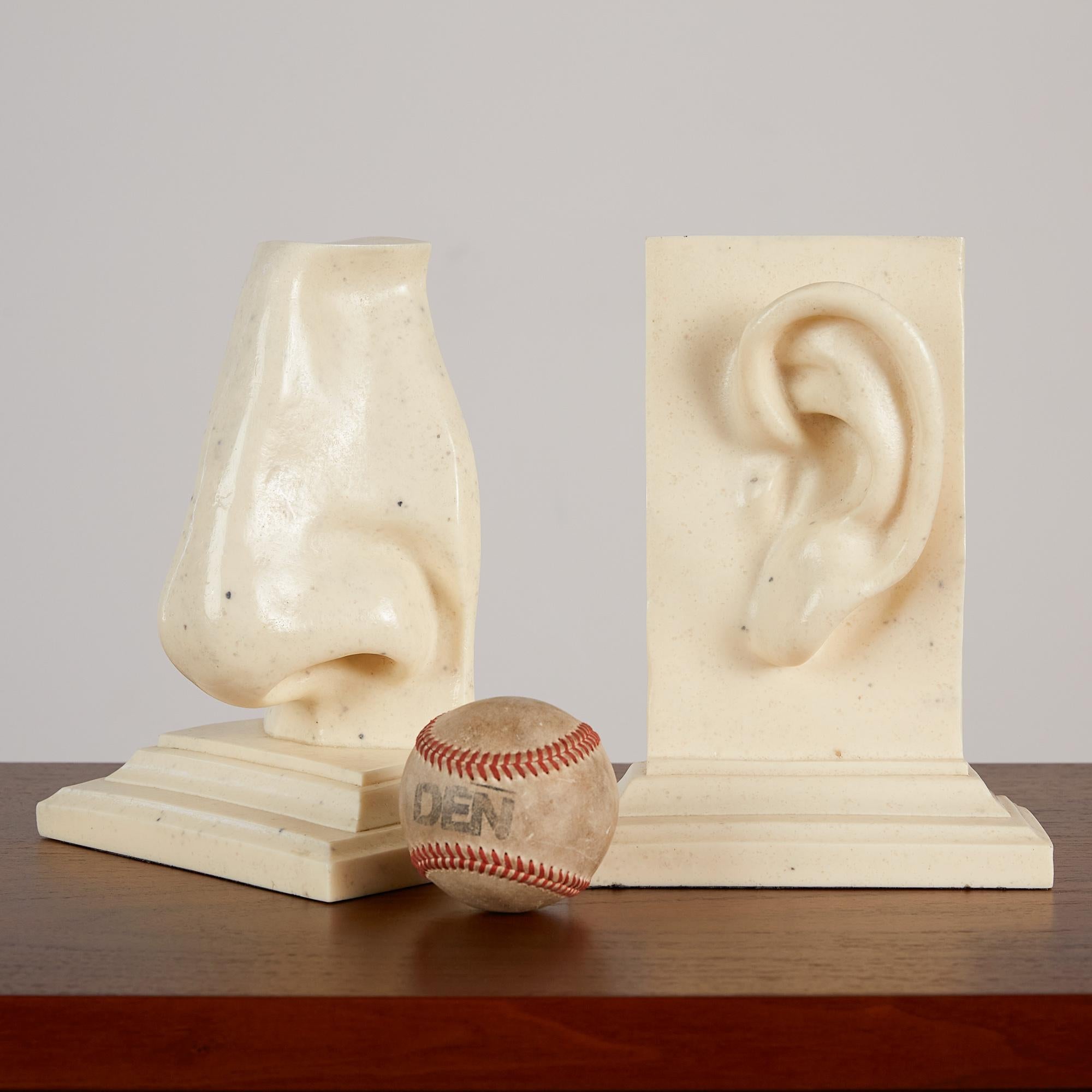 A resin composite ear and nose bookend set by C2C Designs, c. 1980s. These playful bookends have the look of alabaster. Perhaps they remind you of something out of a museum? They are replicas of Michelangelo's nose and ear. The perfect quirky
