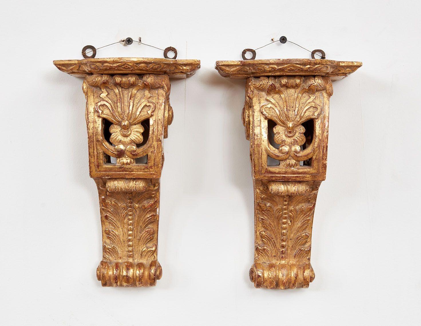 A pair of elaborate gilded wall brackets having shaped platforms resting on scrolled supports with intricately carved acanthus decoration.  French Regence period, circa 1720. 