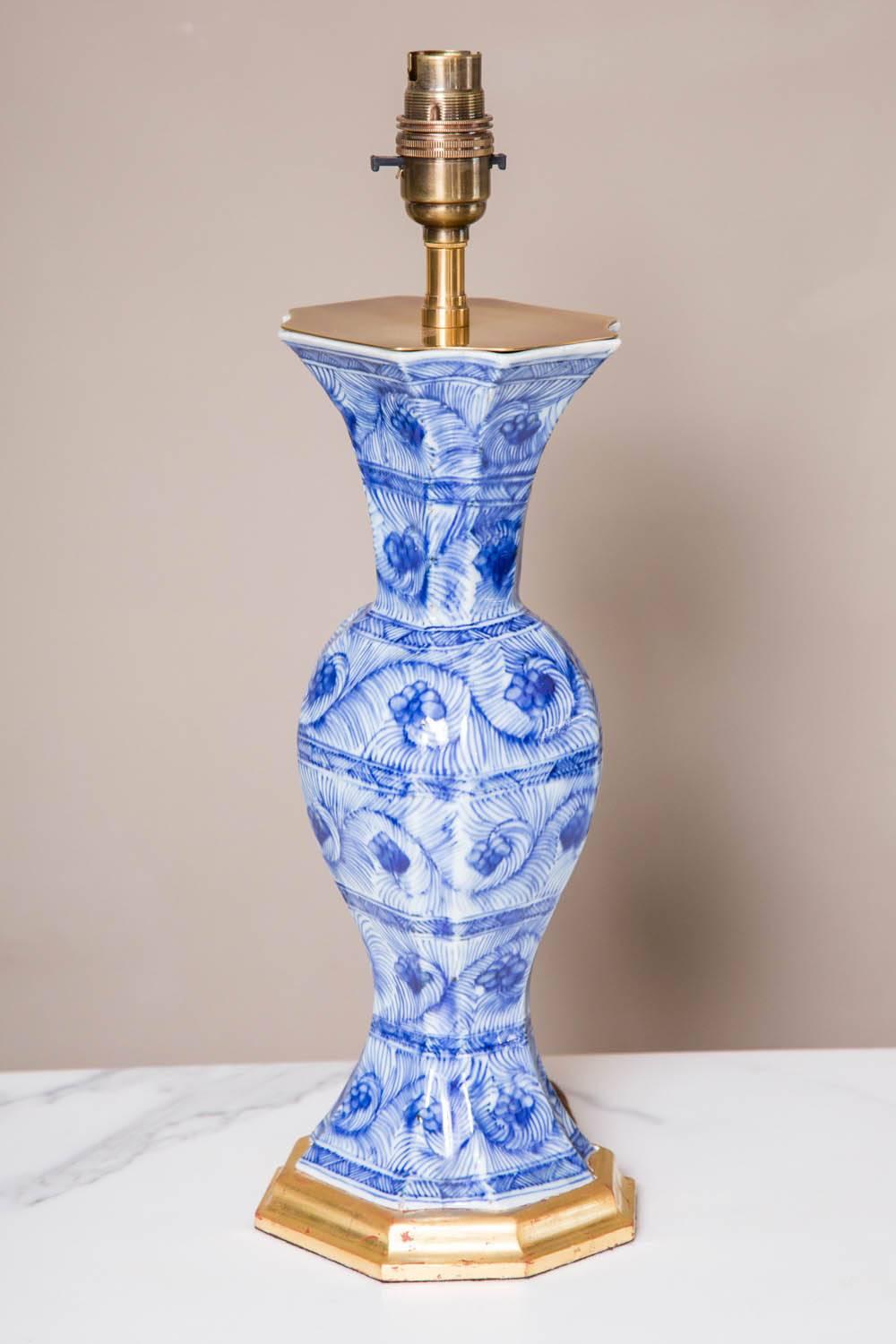 A pair of early 18th century Chinese blue and white vases mounted as lamps. The vases of tapering form and now mounted on hand-turned gilt wooden bases and fitted with antiqued brass caps. The size of these vases make perfect bedside or sofa table
