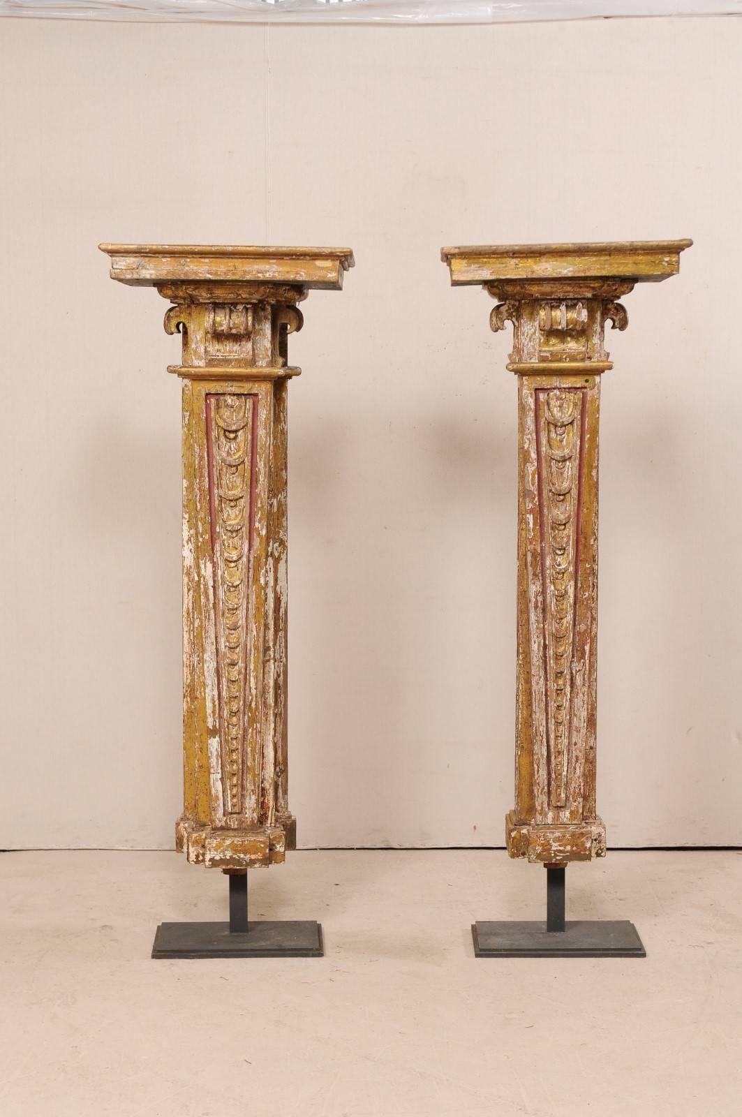 A pair of Italian columns, from the early 18th century, displayed on iron stands. This exquisite pair of early 18th century architectural columns from Italy, standing at over 6 feet tall, have gesso and gilt over wood, with carved frieze vertically