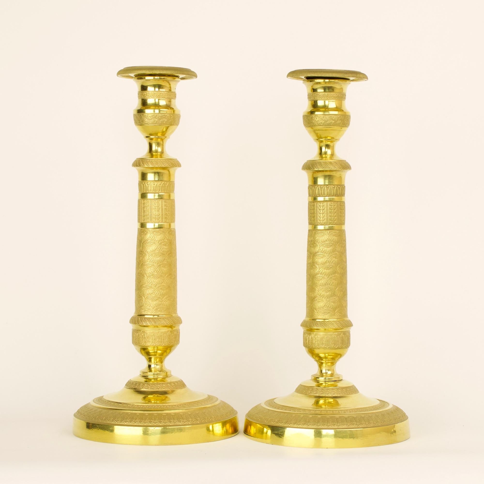 Excellent pair of early 19 century French empire gilt bronze neoclassical candlesticks.

A tapering stem with rich and finely chased relief decoration depicting stylised flowers and foliage friezes as well as an unusual marguerite or daisy onament