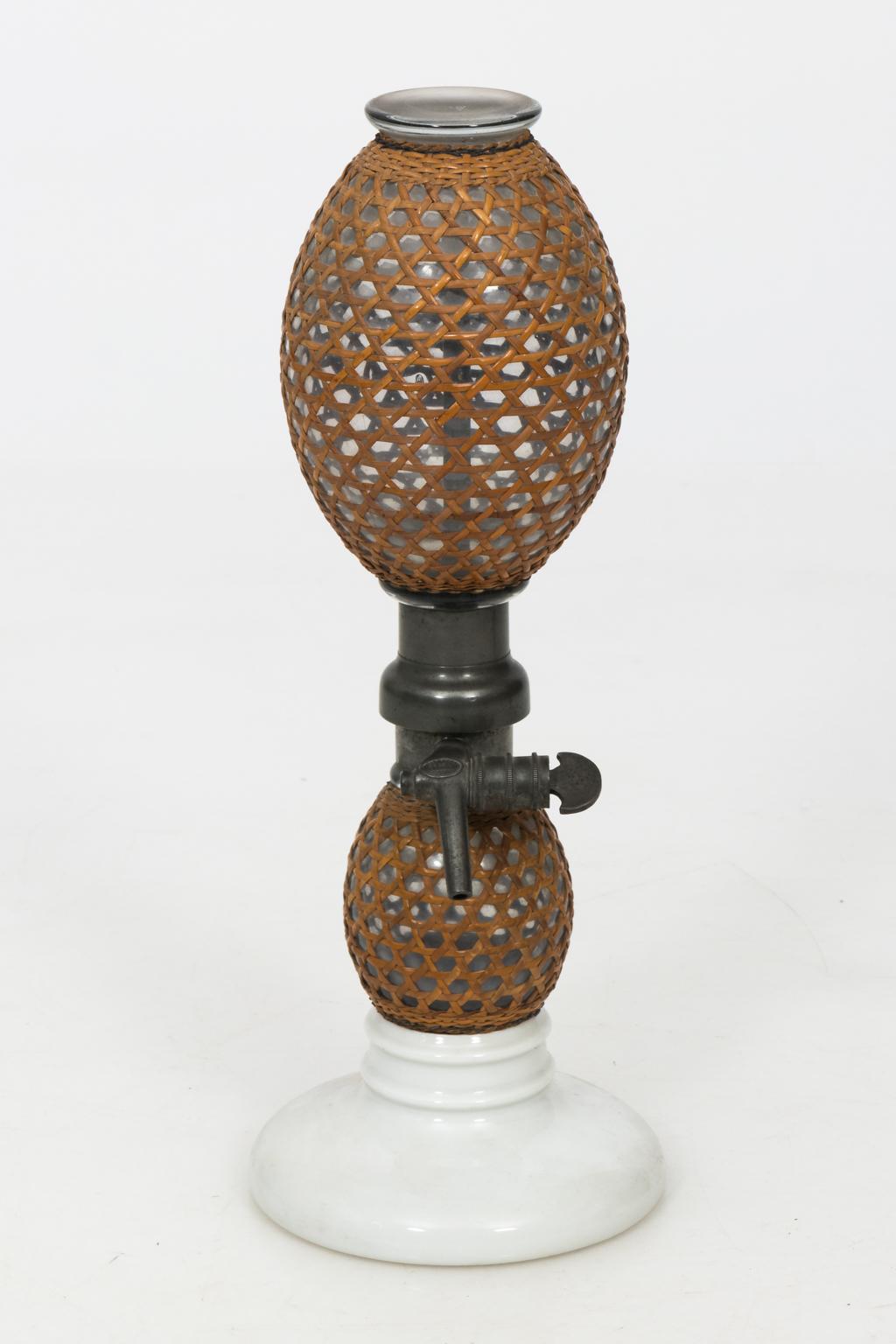 Pair of early 1900s French antique seltzer bottles with cane woven cover.