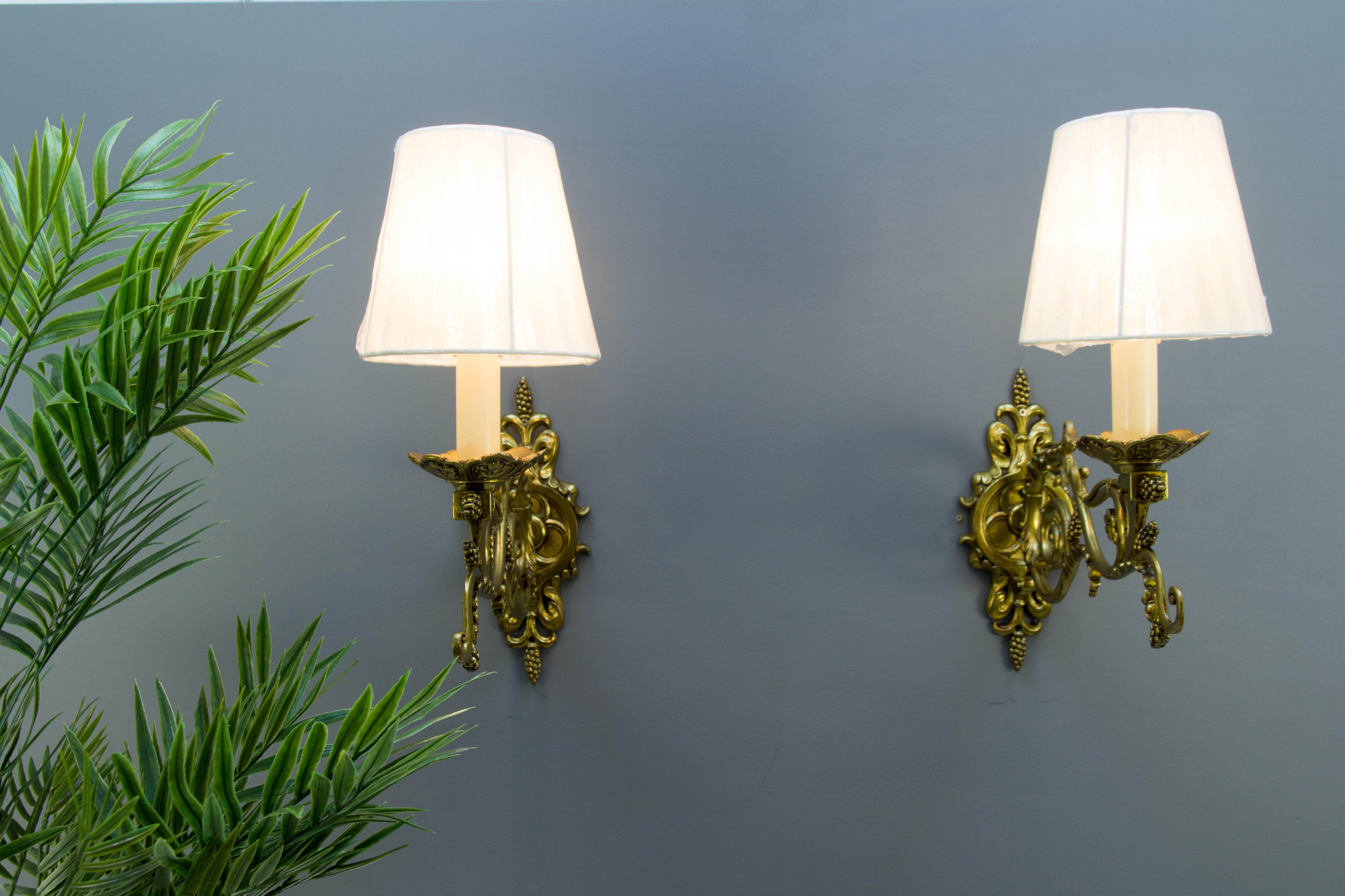 A beautiful pair of French Louis XVI-style wall lights. Made of bronze in the shape of large scrolls and decorated with elegant foliate motifs. Each sconce has one socket for the E14 size light bulb and a new fabric lampshade.
Dimensions (each