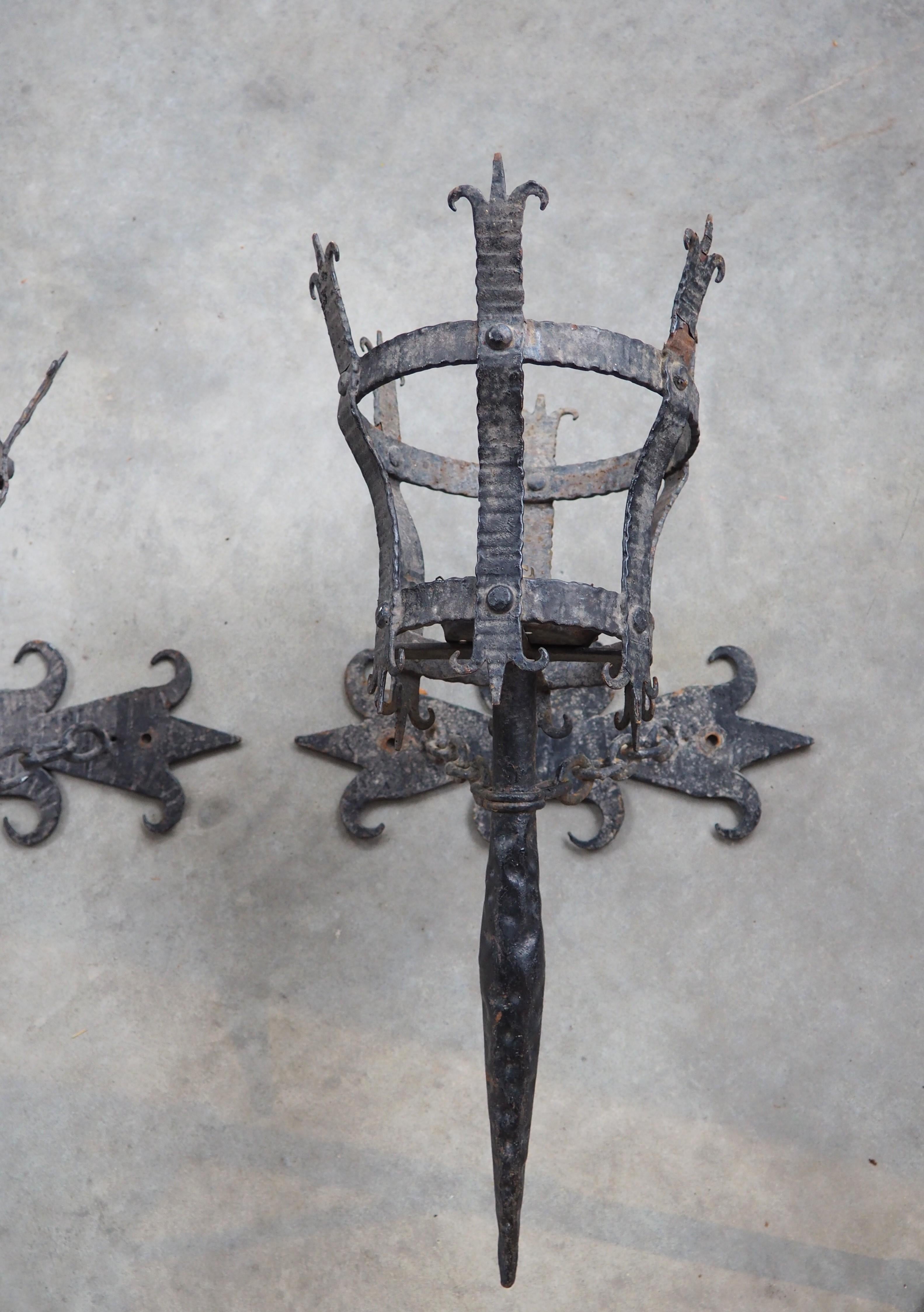 More information coming soon…

This pair of wrought iron torch sconces are in the style of the Medieval period.  Dating to the early 1900s, the sconces have a painted black finish that augments the robustness of the angular and barbed backplate, the