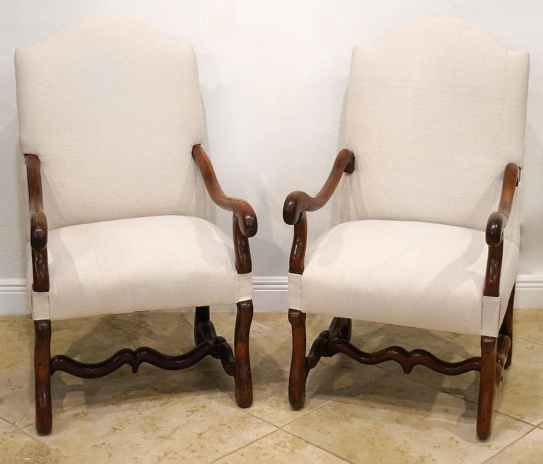 These magnificent French Provincial arm chairs in the baroque style feature a high arched backrest and down swept carved armrests on serpentine shape supports rising from the seat frame. The serpentine carved legs are united by shaped stretchers.