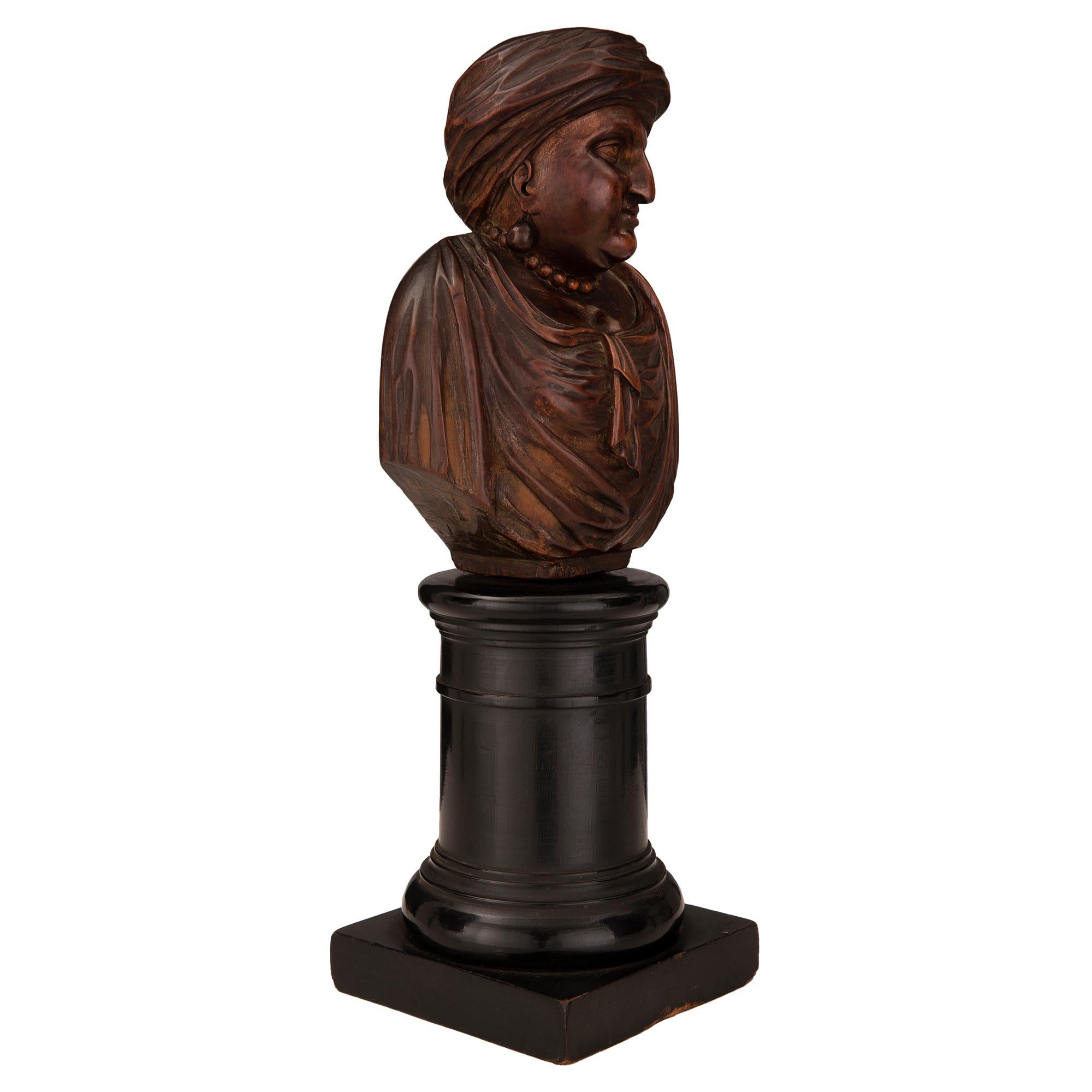 A charming and finely detailed pair of early 19th century carved walnut and ebonized fruitwood busts of Turkish nobles. Each bust is raised by a square ebonized fruitwood base with an elegant circular mottled central support. The richly carved