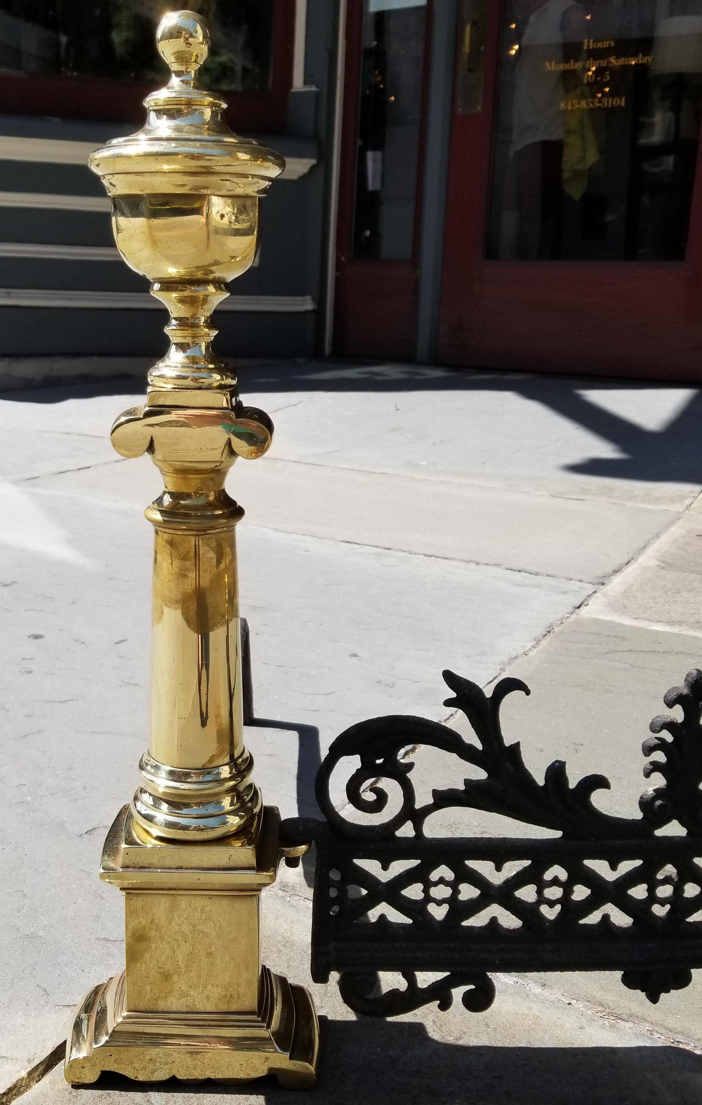 A rare pair of Charleston neoclassical brass andirons, circa 1810, with the original cast iron fender. The total width of the andirons and fender set is 24.75