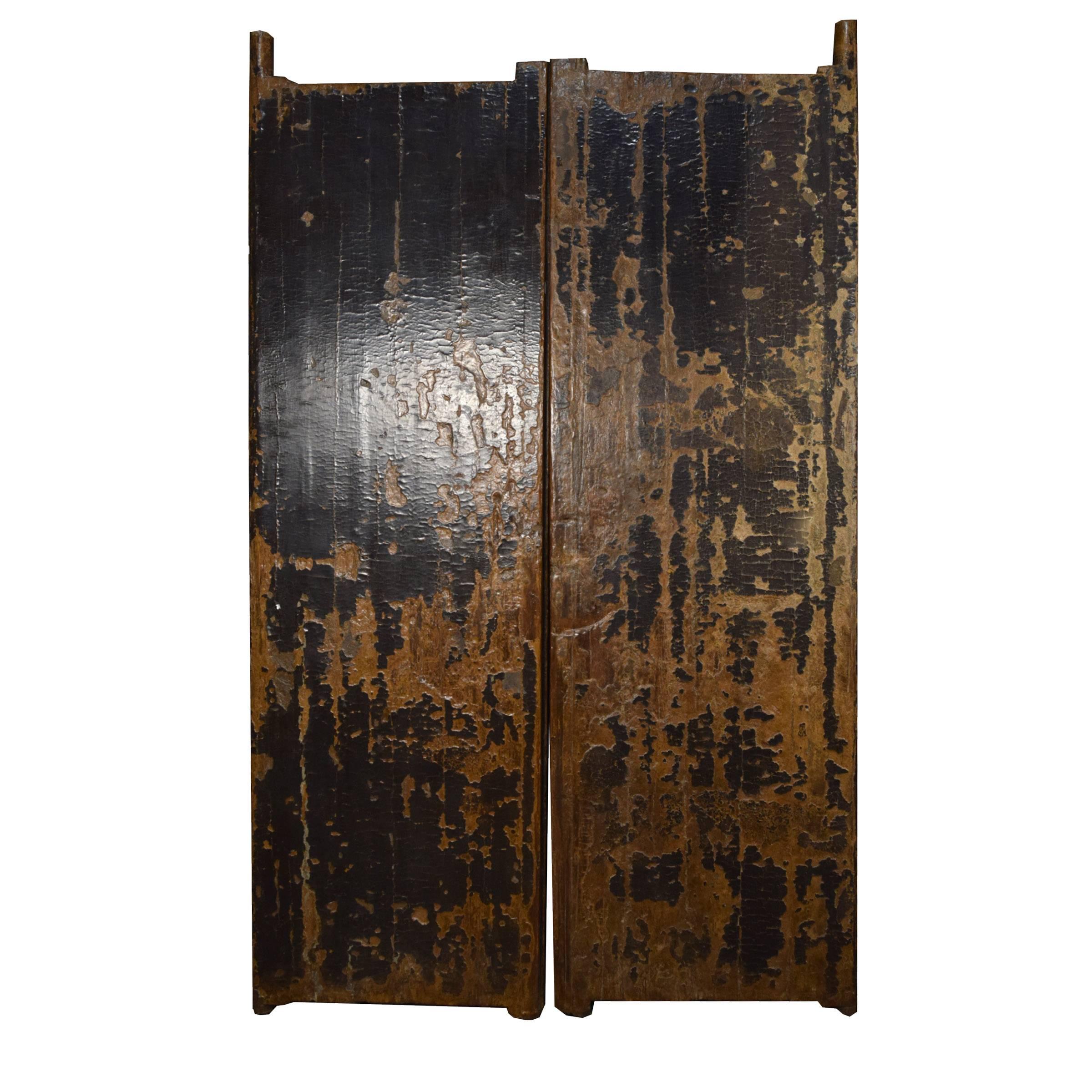 The countless coats of hand-applied black lacquer have aged with an inimitable crackle on this pair of 19th century doors, which would have originally been the outermost entrance gates to a traditional home in Northern China. The graphic marks on