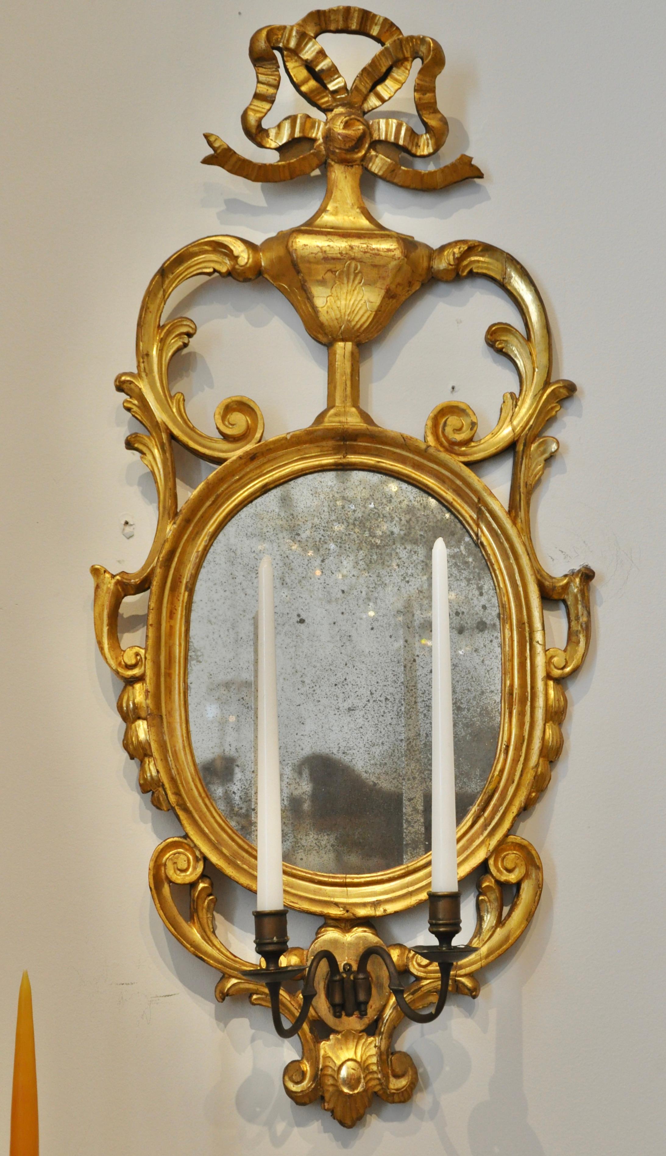 Pair of early 19th century continental sconce mirrors with original early glass and original gilding. Two arm sconces for candles. Great size and wonderful original water gilt carvings. Neoclassical ribbon top motif. Probably Danish in origin.