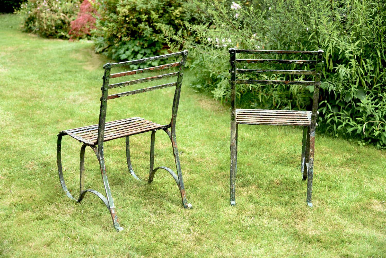 A fine and rare pair of English Regency period wrought iron garden side chairs, each with four strap back rails over 's' curved side frames. 
Showing a multitude of ancient coats of paint and many years of healthy neglect. 

    