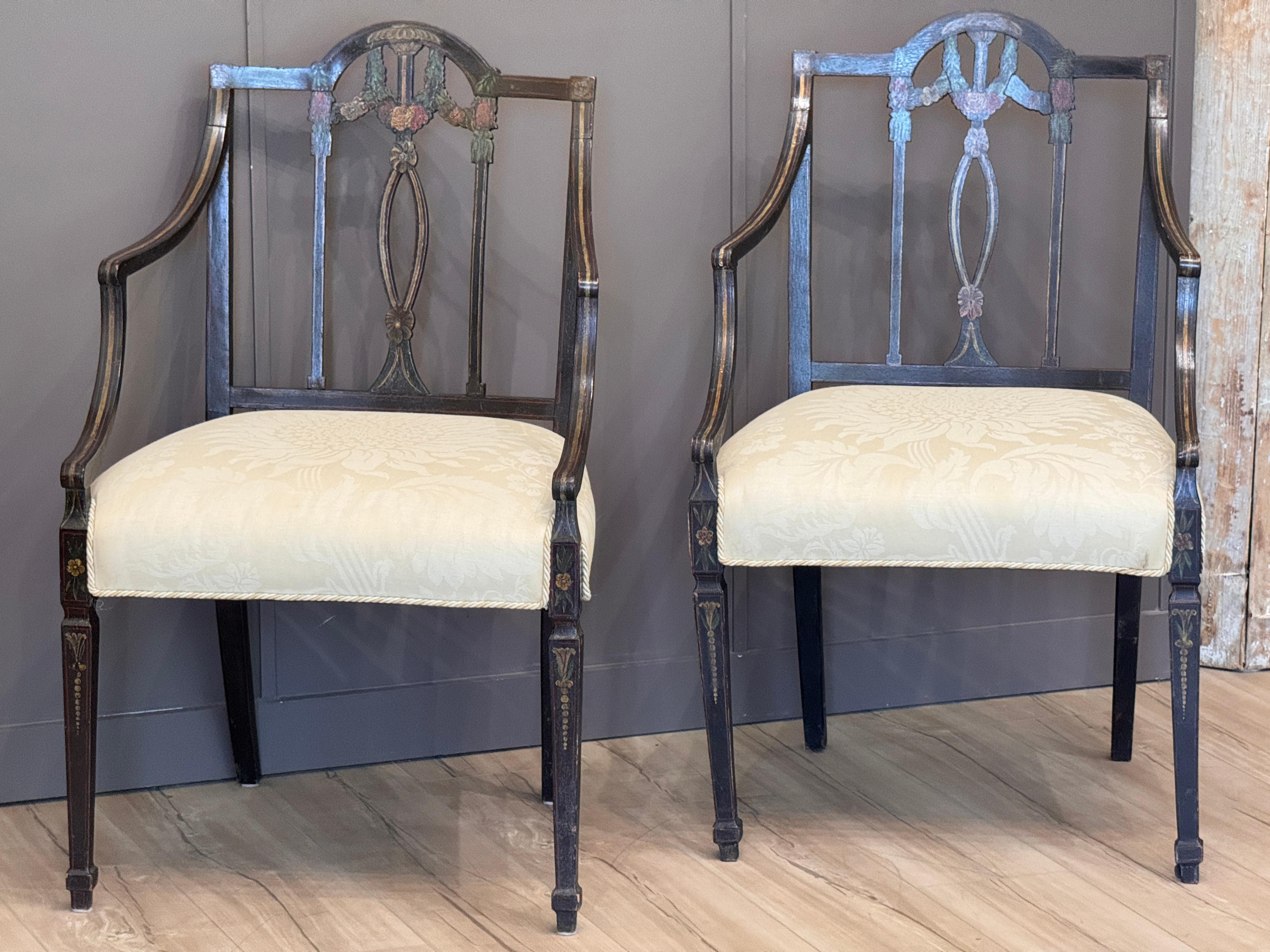 Encantadora pareja de sillones ingleses de principios del siglo XIX con decoración original pintada. Las sillas presentan motivos florales neoclásicos en tonos suaves y envejecidos a lo largo del tablero, la barandilla de la cresta y las patas