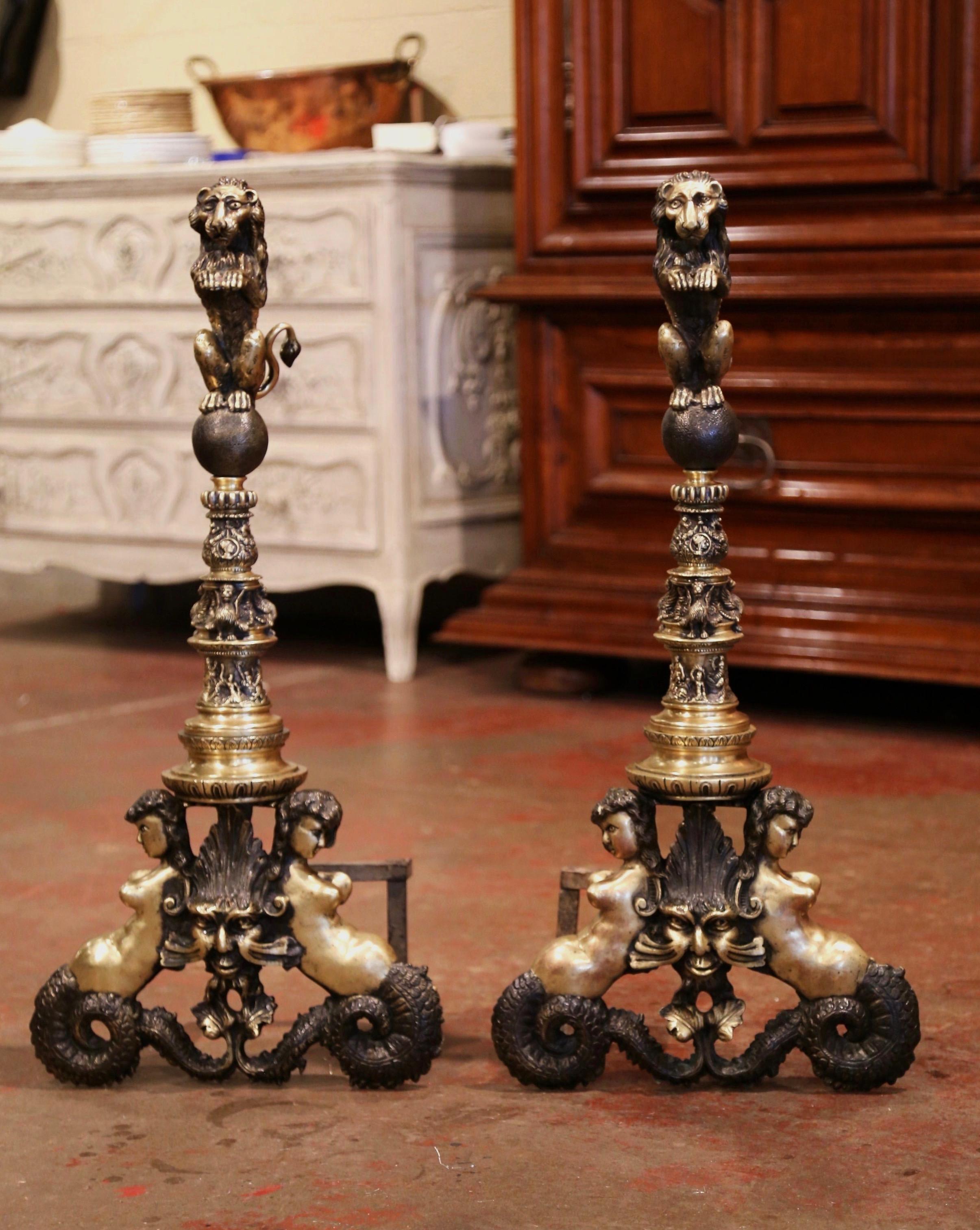 Decorate a fireplace hearth with this elegant pair of antique chenets; crafted in England circa 1830, each heavy bronze andiron is decorated at the base with mermaid and grotesques motifs. The tall stem with intricate rings is decorated at the top