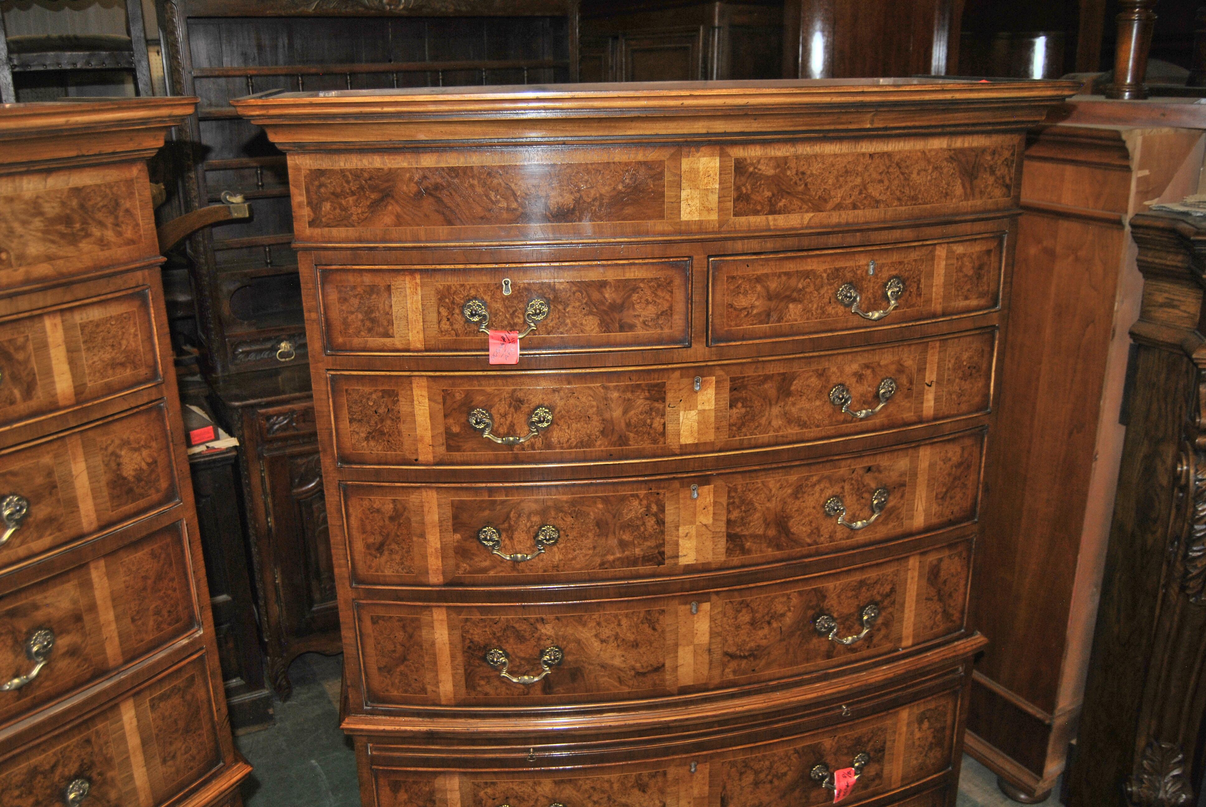 This is a pair of bow front chest on chests / highboys that were made in England, circa 1820. Each chest has a beautiful, well layered crown molding to the top. The upper half of the chest has 2 small drawers over 3 long drawers that are graduated