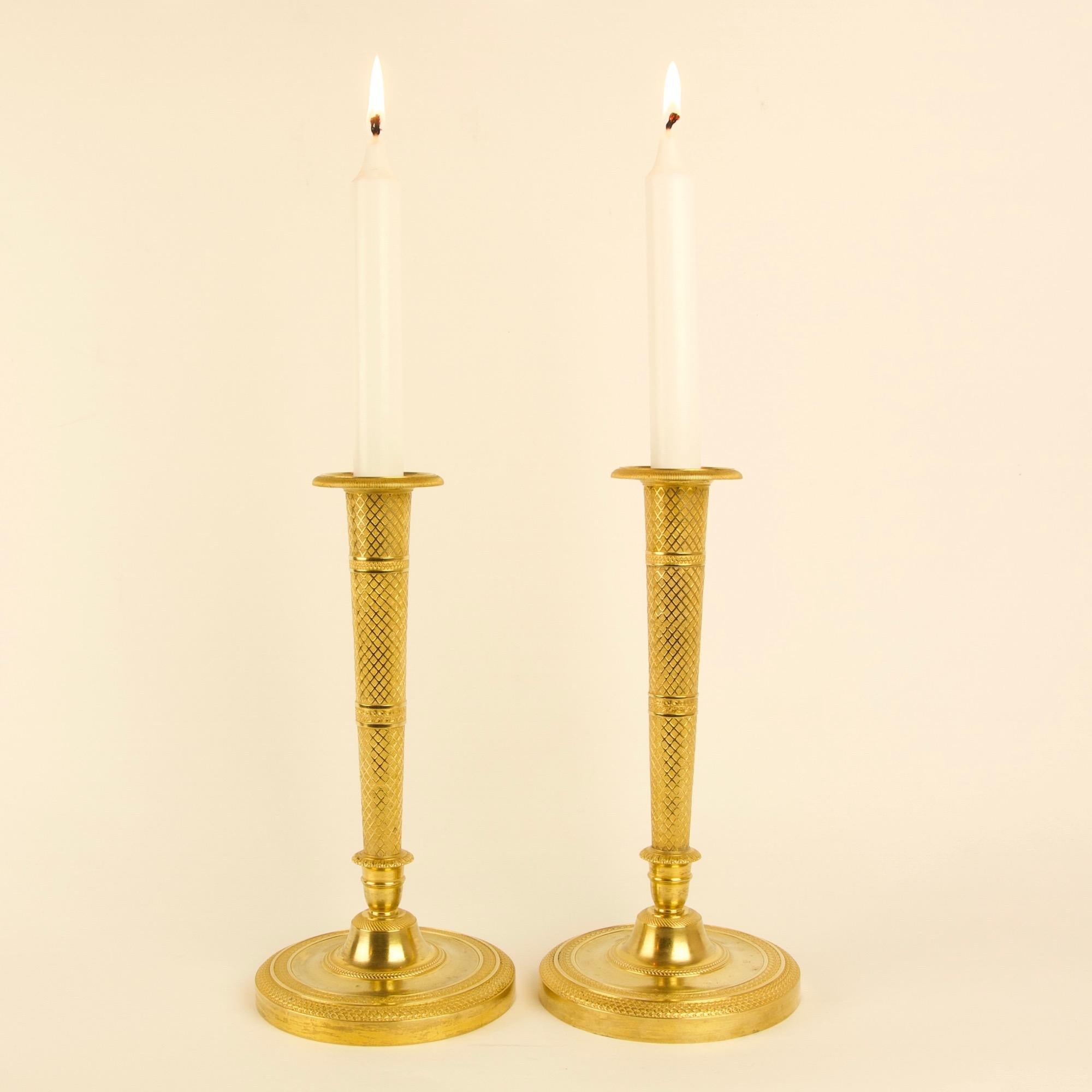 Pair of excellent early 19th century French empire gilt bronze candlesticks in the style of Claude Galle (1758-1815):

A tapering stem with rich trelliswork relief divided into three sections by two rings with foliage and lozenge decoration raised