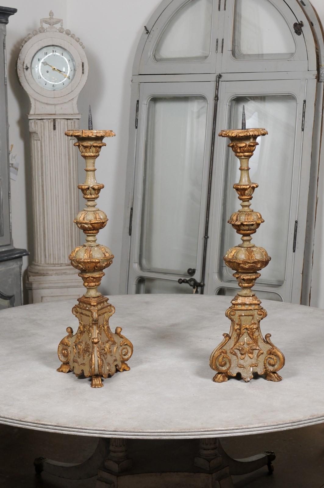 A pair of French Rococo style painted and carved wooden candlesticks from the 19th century, with gilt accents. Created in France during the early years of the 19th century, each of this pair of candlesticks features the typical curvature found on