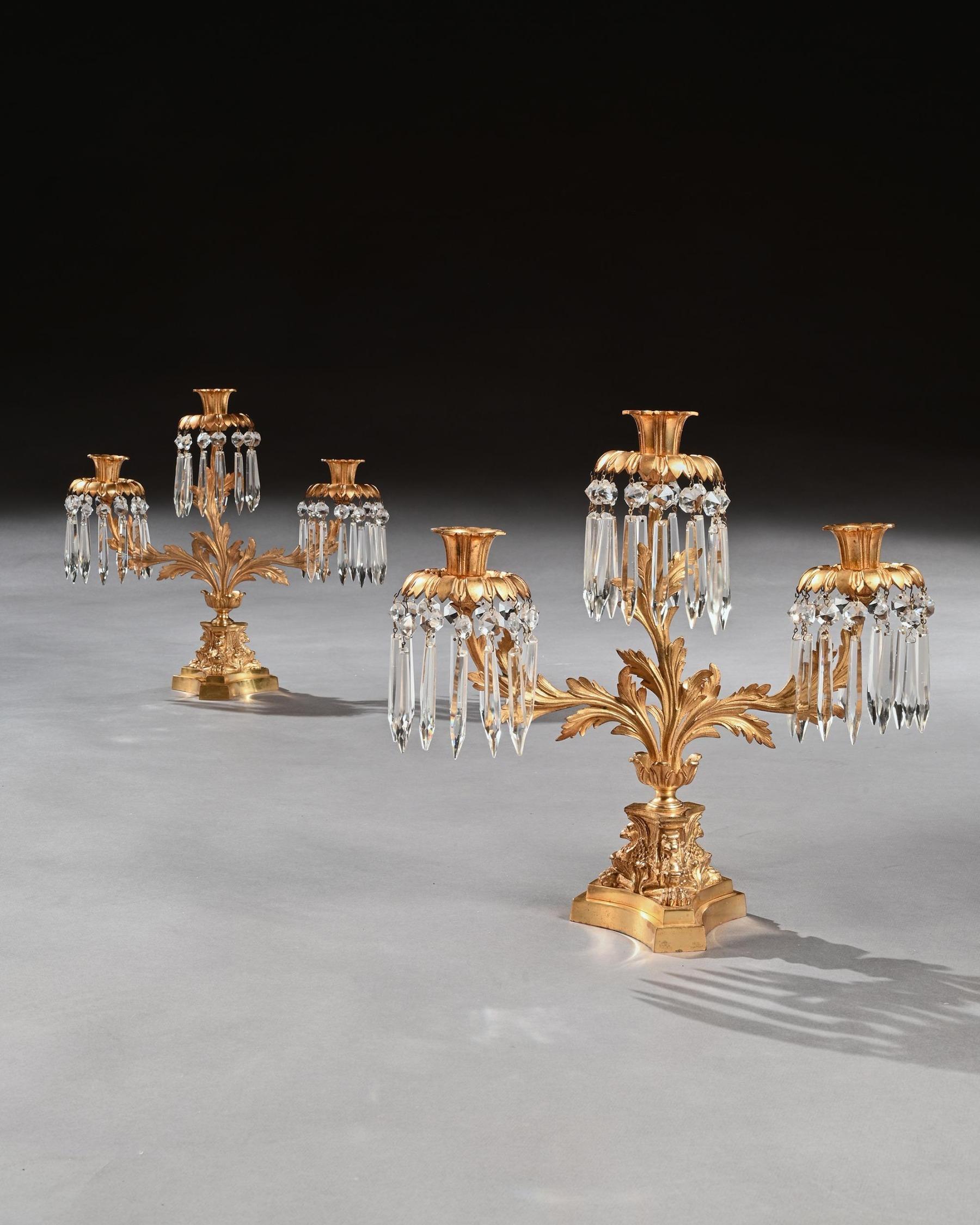 A very attractive pair of early 19th century three branch gilt bronze candelabra with cut-glass lustres.



Probably English Circa 1820.



Of rare form and in wonderful original condition, the three leaf cast branches with tulip nozzles and