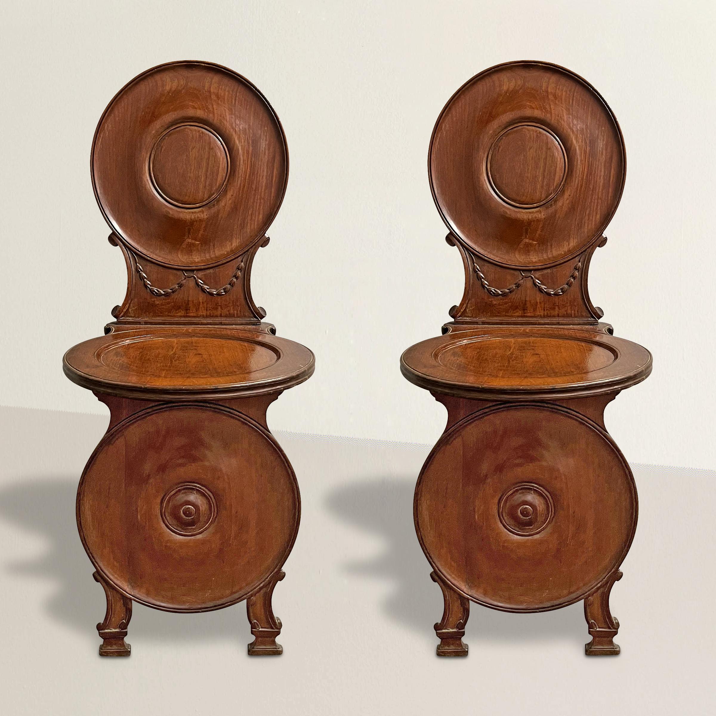 Step into the elegance and grandeur of the Napoleonic period with this exceptional pair of early 19th century Italian mahogany hall chairs. During the Napoleonic period, hall chairs played a significant role in the grand entrances and hallways of