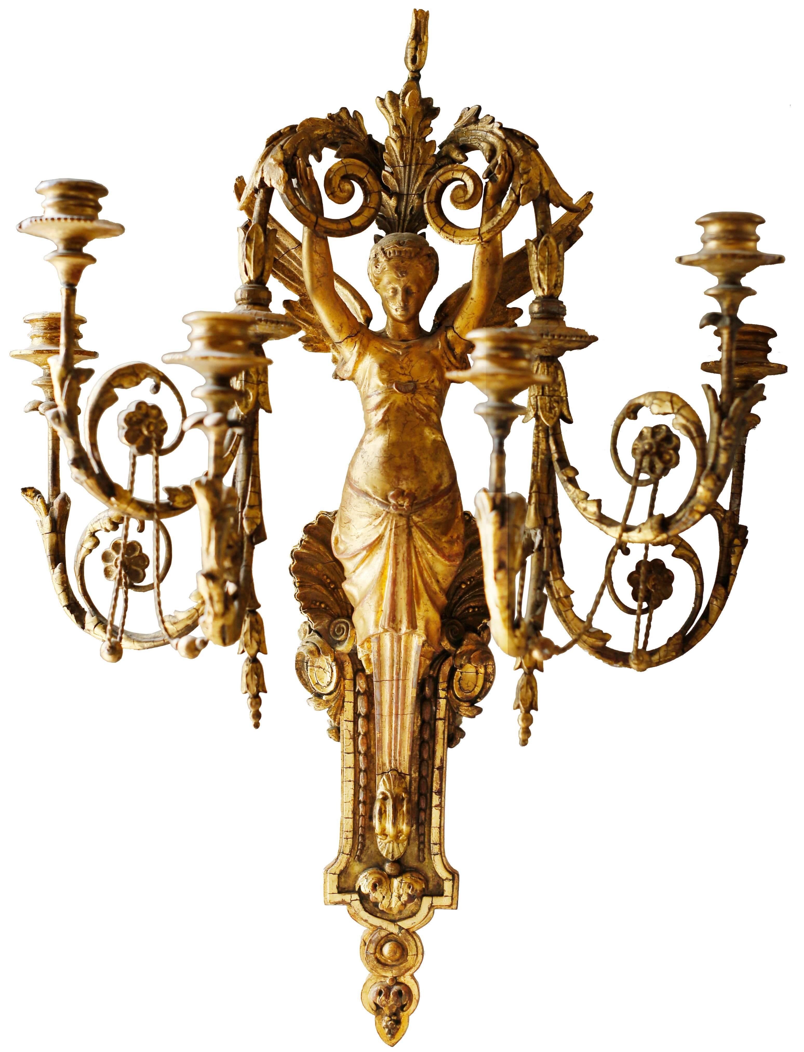 An exquisite pair of giltwood 6-light wall sconces. The light is supported by the figure of a winged seraphim whose draped lower half melds into a moulded bracket and acanthus pendant. The upper half of the bracket is decorated with a large scallop