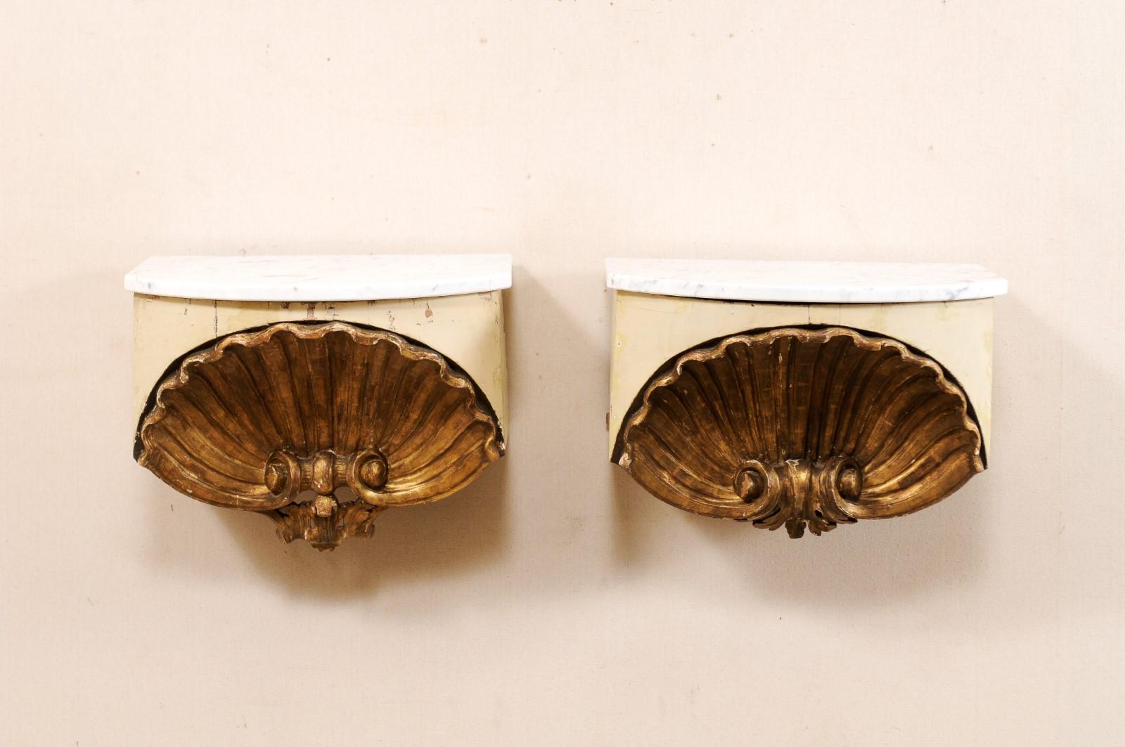 A pair of Italian early 19th century carved shell wall shelves, similar in appearance, with marble tops. This small pair of decorative wall displays have been custom fashioned from early 19th century (or earlier) Italian shell-carved wood fragments,