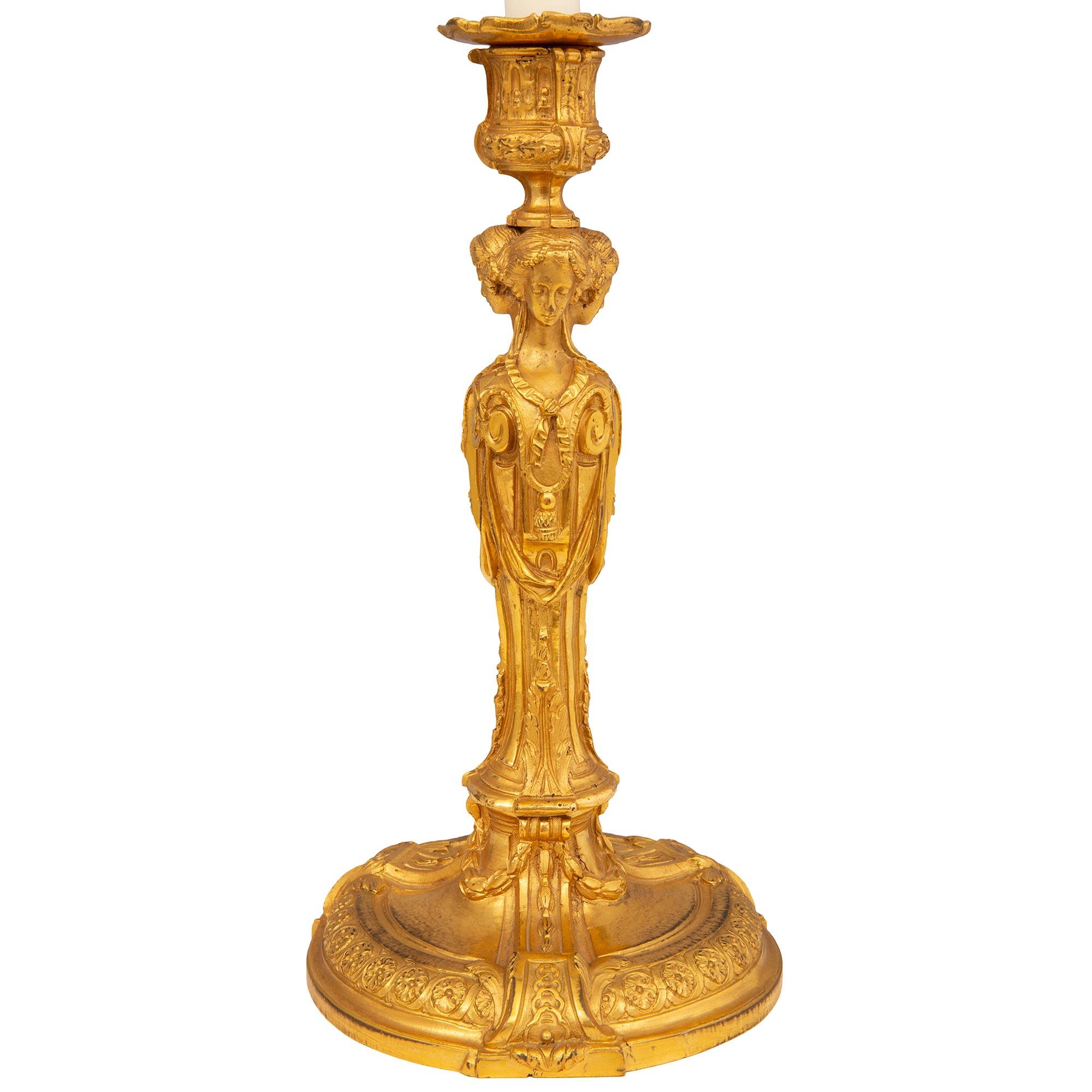 Une belle paire de chandeliers français du début du 19ème siècle, de style Louis XVI, en bronze doré. Chaque chandelier est surélevé par une base circulaire au motif finement marbré et des bandes enveloppantes très décoratives aux motifs