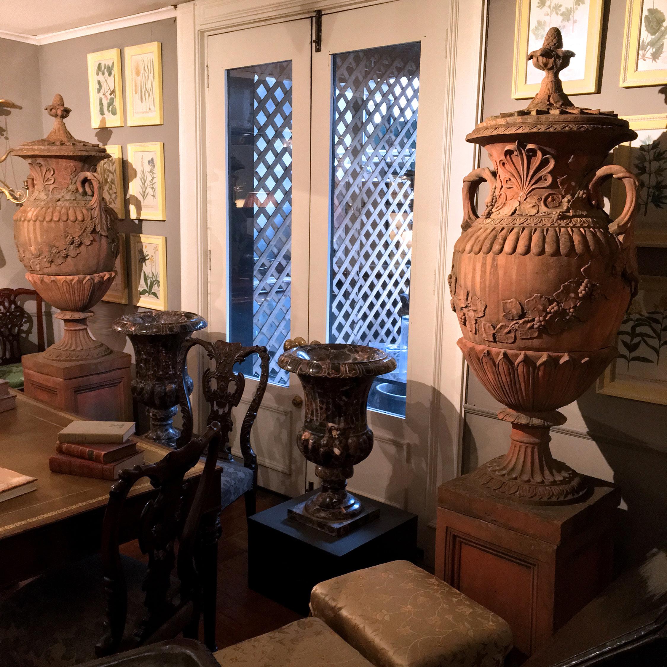 Each of this pair of large early 19th century terracotta campagna urns, in the neoclassical style, sits atop a molded socle plinth base, its baluster body ornamented with gadrooning, foliate and grape-vine motifs cast in relief, and with scroll