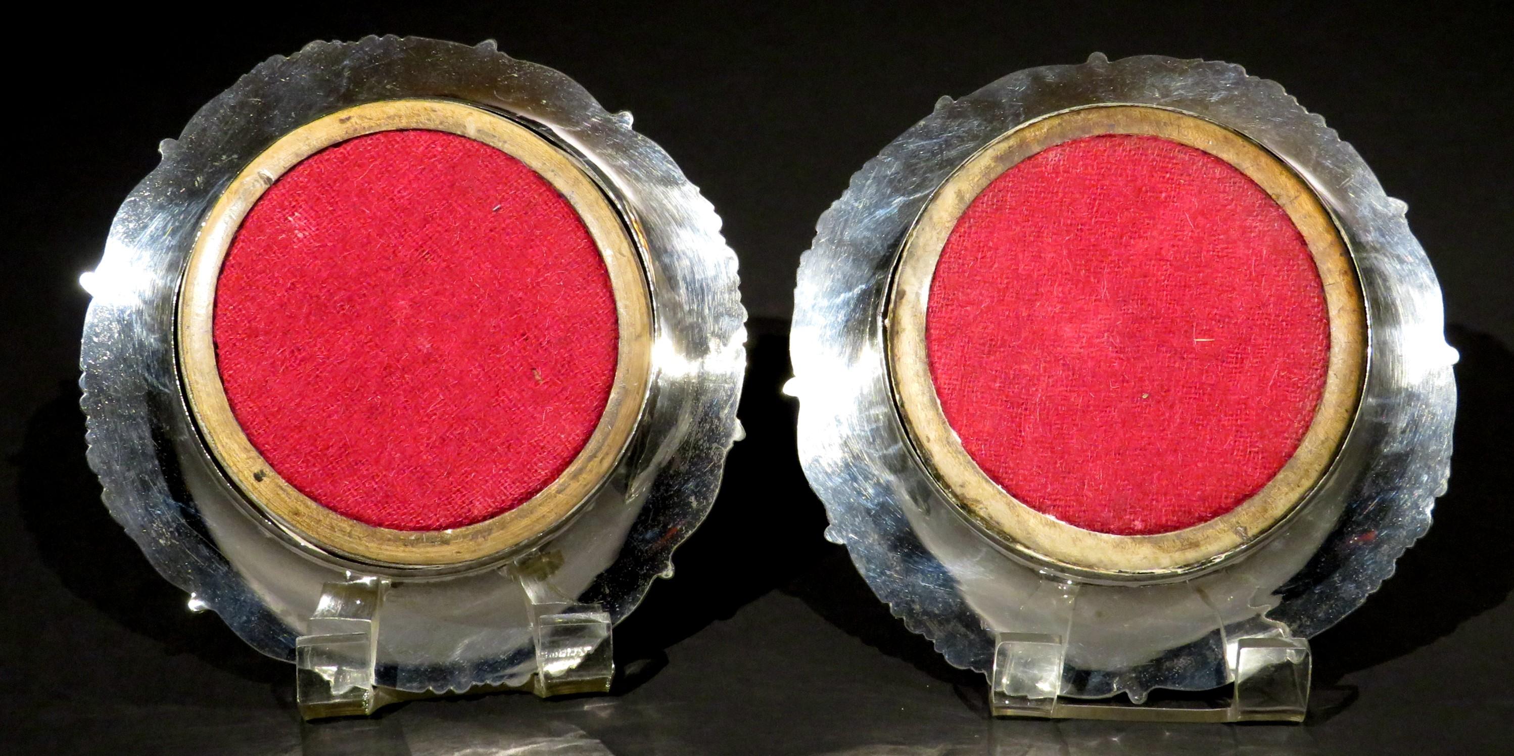 A very handsome pair of re-plated 'Old Sheffield Plate' wine or decanter slides / coasters, both showing rims decorated with shell & scroll cast motifs, rising from turned wood bases centered by plated roundels, their undersides lined with red
