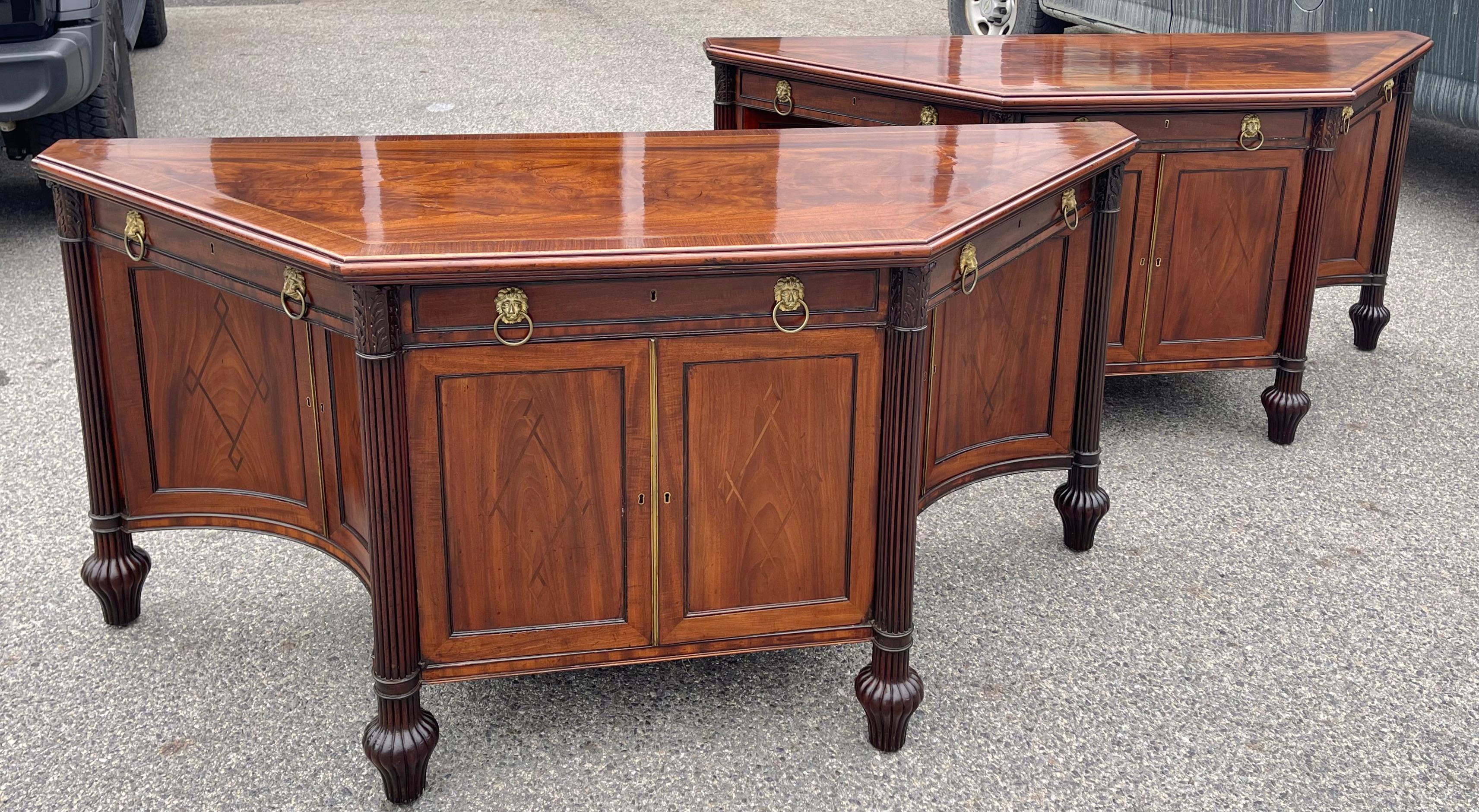 Rare pair of Regency or Late Georgian Inlaid Mahogany sideboard cabinets. Wonderful trapezoidal form with concave side doors and interior shelving. Drawers with original lion pulls. Reeded columns and amphora feet.

Provenance: Winter Antique