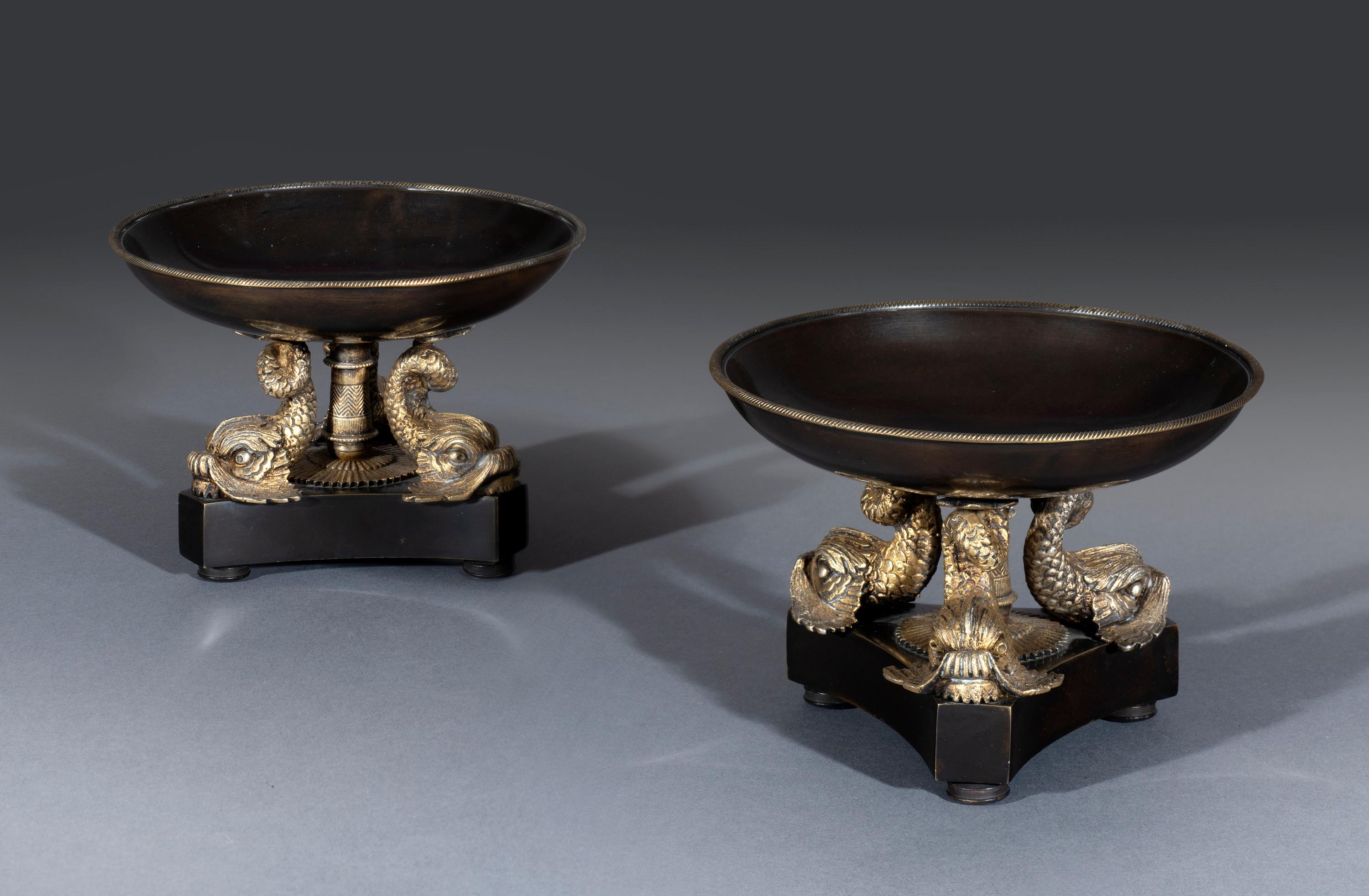 Pair of early 19th century Regency period bronze and gilt ormolu tazzas attributed to Thomas Messenger & Sons (1810 to 1930)

The dish tops are mounted with gilt brass moundings surmounted on crisply cast 'Dolphin supports' and a central column.