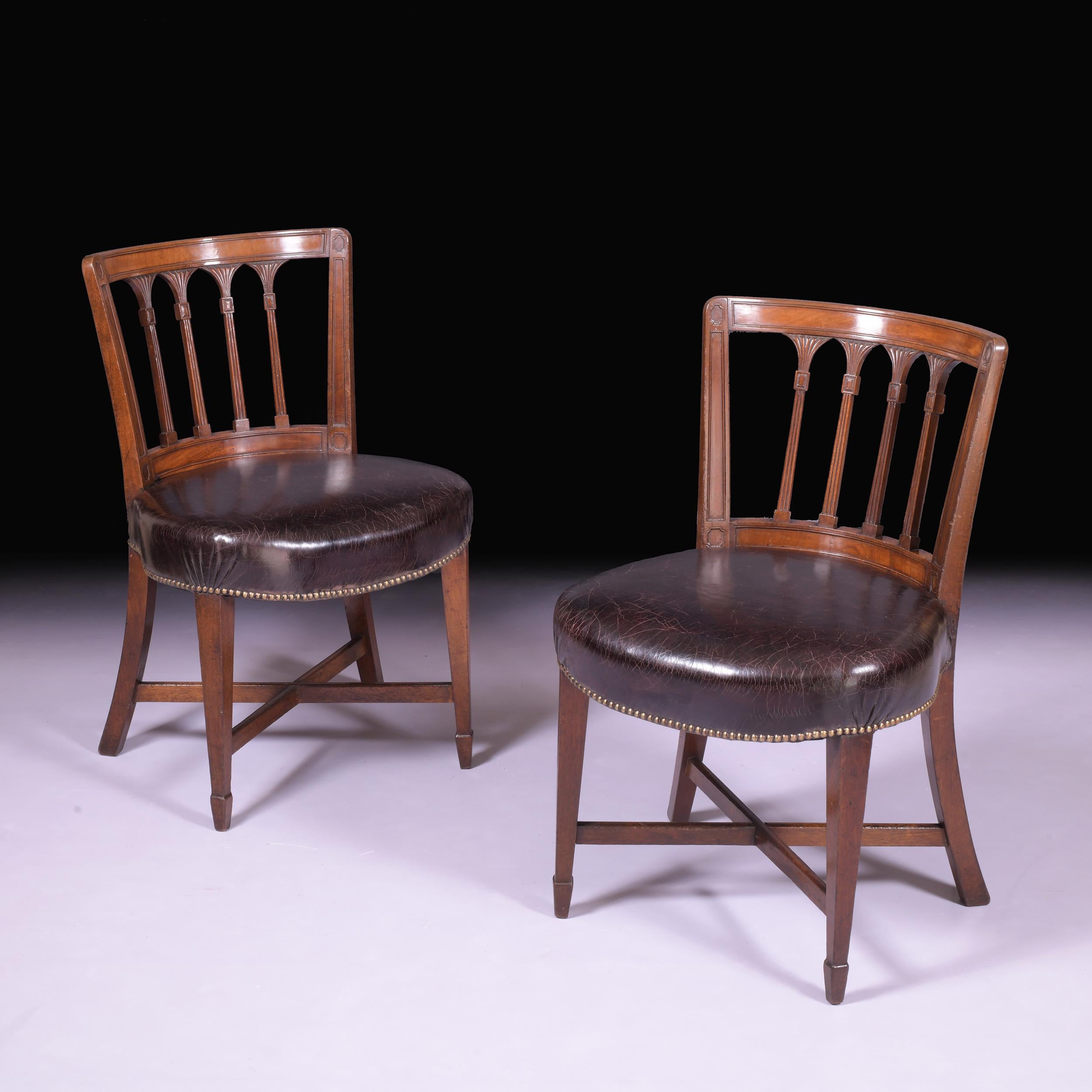 A stunning pair of Regency mahogany side chairs attributed to Gillows of Lancaster, each moulded curved back with pierced fluted rail backs above leather stuff-over seats and brass close nail decorated rails, raised on square tapering front legs and