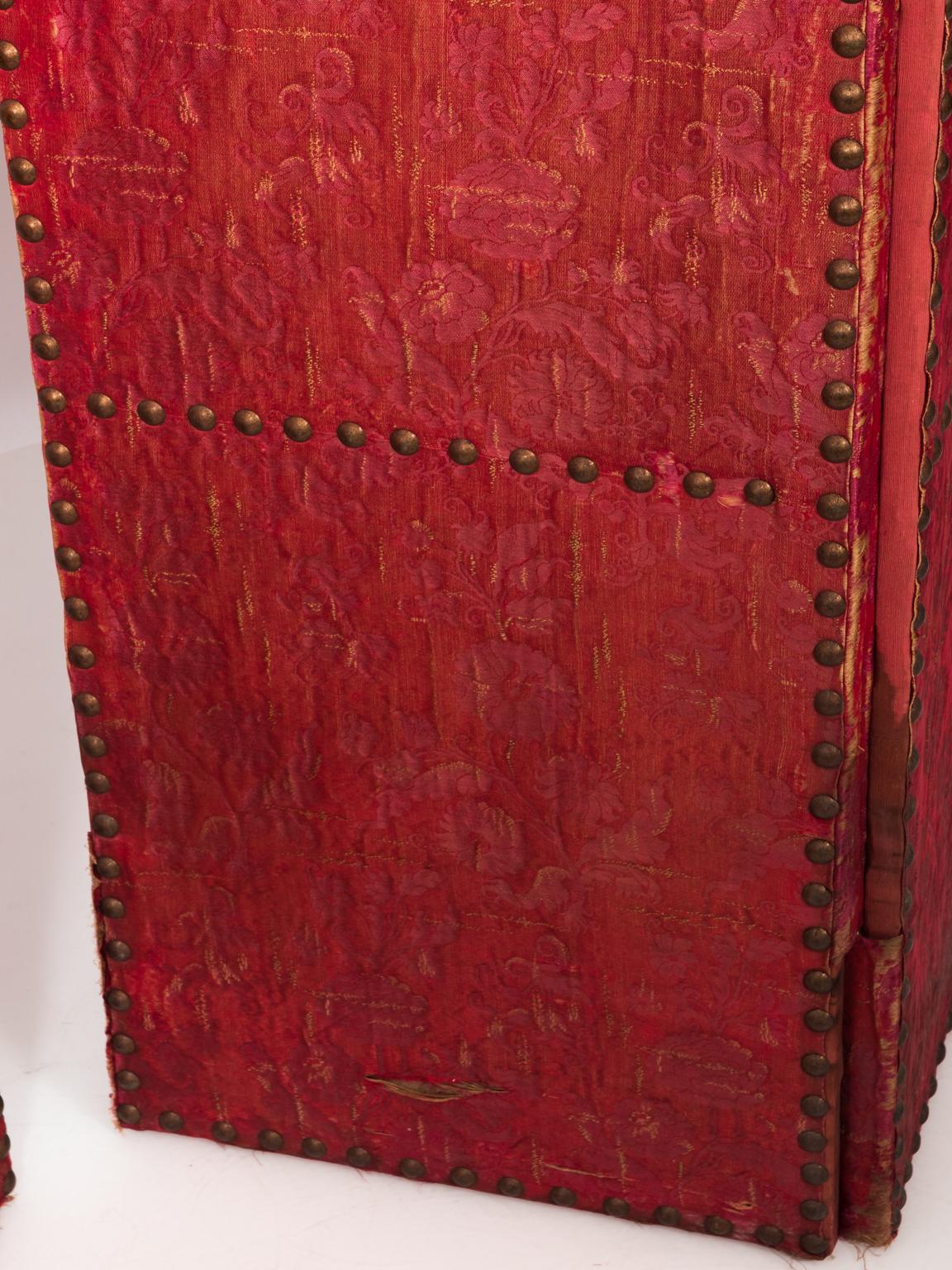 19th century Italian red silk damask on Moorish style screens with large nailheads. There are tears, and signs of discoloration in the silk. The fabric is original, dating back to early 19th century.
 