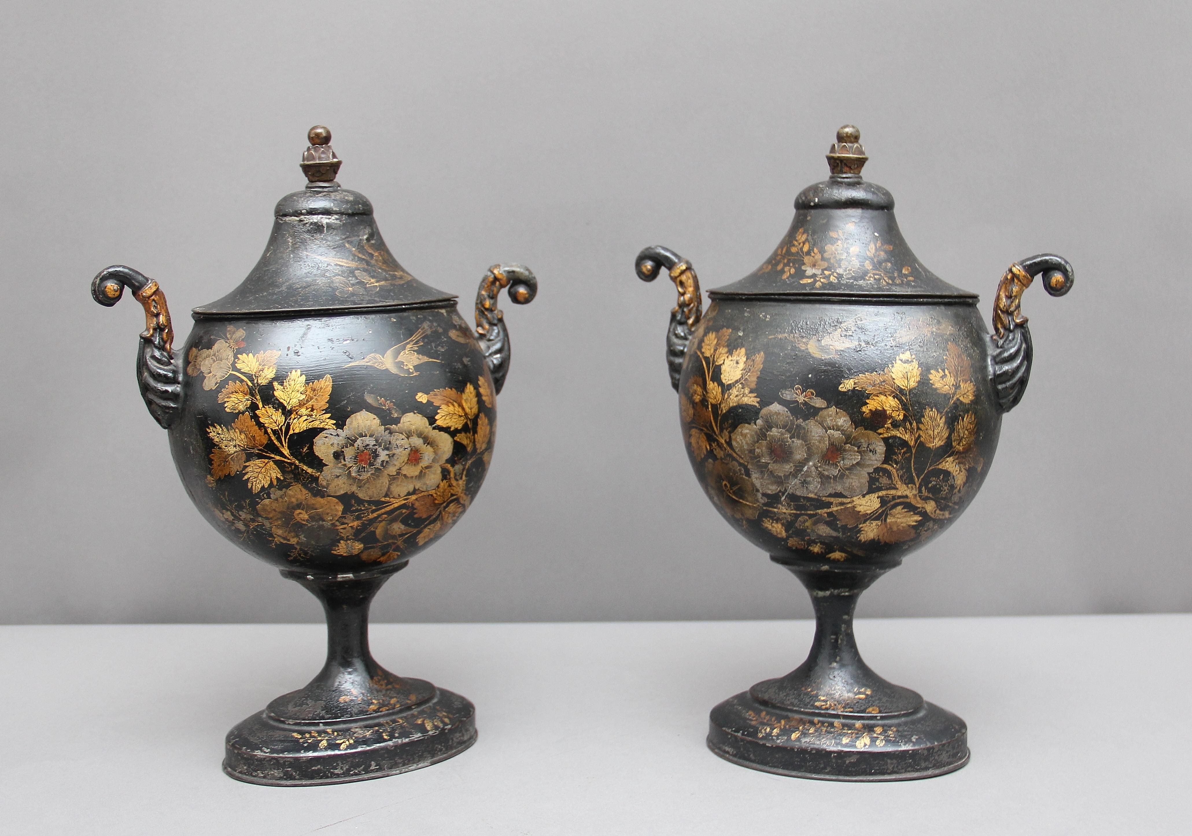 A rare pair of early 19th century toleware chestnut urns, decorated with flowers, birds and butterfly’s in lovely colors, standing on oval bases and with scrolling arms, the lids topped with brass finials. Hot chestnut urns were popular in the late