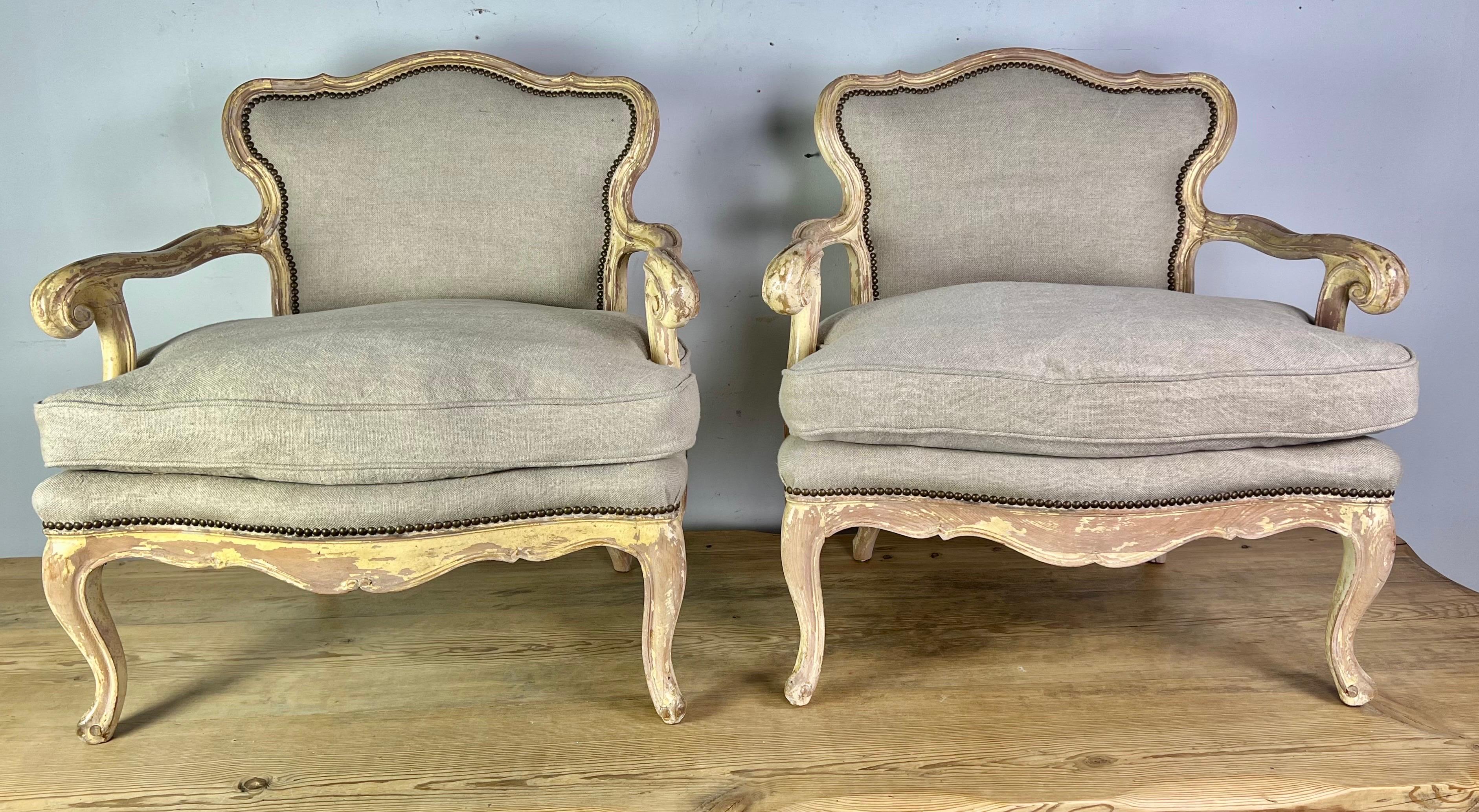 Early 20th century French Provincial pair of armchairs. The chairs have a unique shape with beautiful curves throughout. They were originally painted but only remnants of paint are left behind. The chairs stand on four cabriole legs with rams head