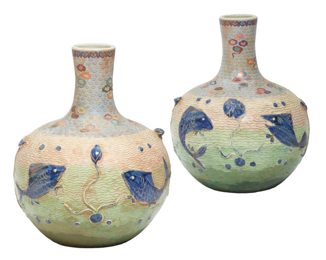 Behold a remarkable pair of early 20th-century Chinese cloisonné enameled porcelain vases, harkening from the 1900s. These vases are a visual symphony, adorned with intricately molded relief, featuring a mesmerizing aquatic tableau of fish in a