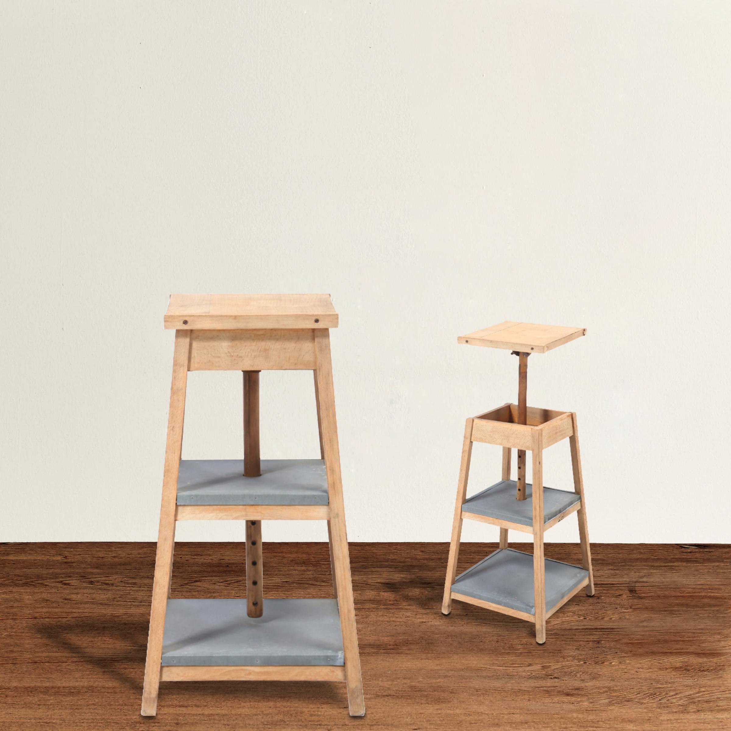 A wonderful pair of early 20th century American beech artist's sculpture tables with adjustable tops and each having two shelves lined with zinc. These are perfect as plant stands, side tables, pedestals for objet d'art, or used in a bathroom for