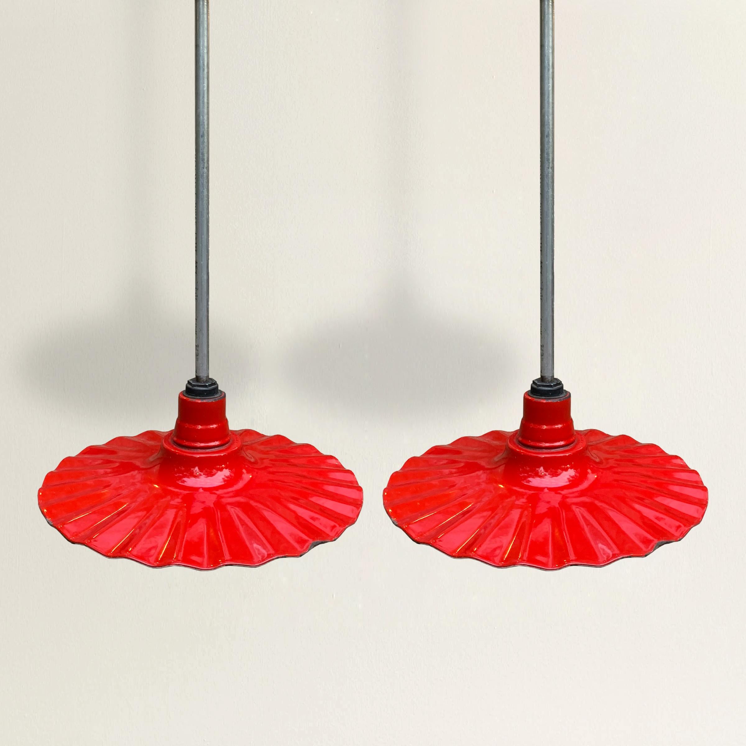 A wonderful and playful pair of early 20th century American industrial light fixtures with red enamel ruffled shades. Fixtures have been re-wired for US.