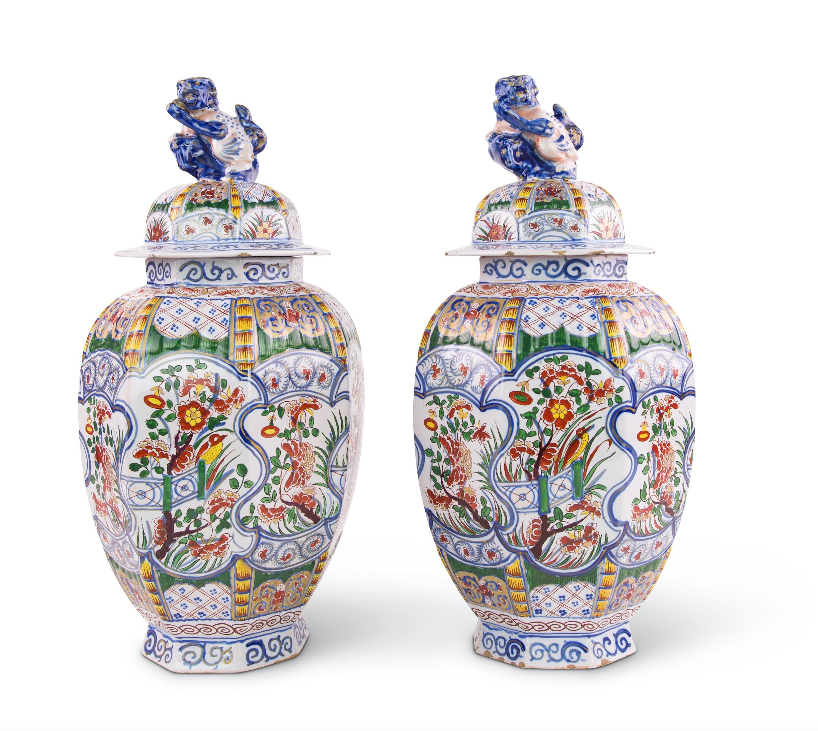 A fine pair of Dutch Delft octagonal polychrome vases and covers, with ribbed bodies and painted panels of flowers and foliage in the famille verte Kangxi style, the palette predominantly green and yellow with blues on a white background. The lids