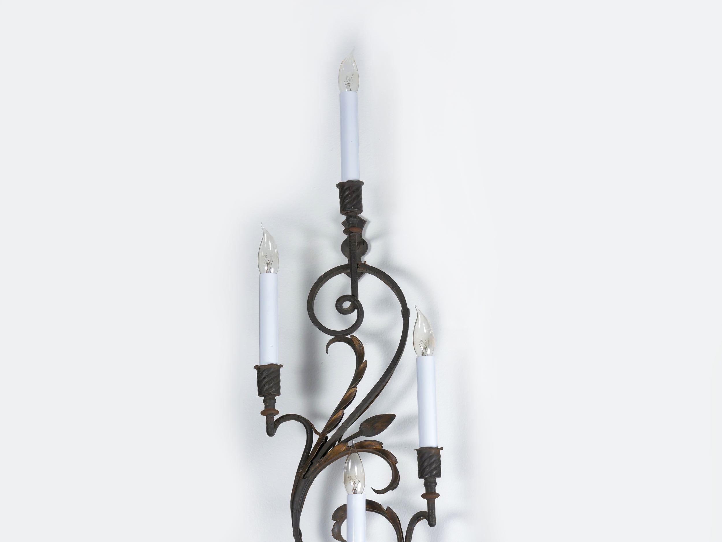 This gorgeous pair of wall sconces is full of intricate attention to detail in the skilled metal work throughout. There is a fine representation of buds and blooming flowers that burst forth from a twisted vine S-curve form complete with hammered