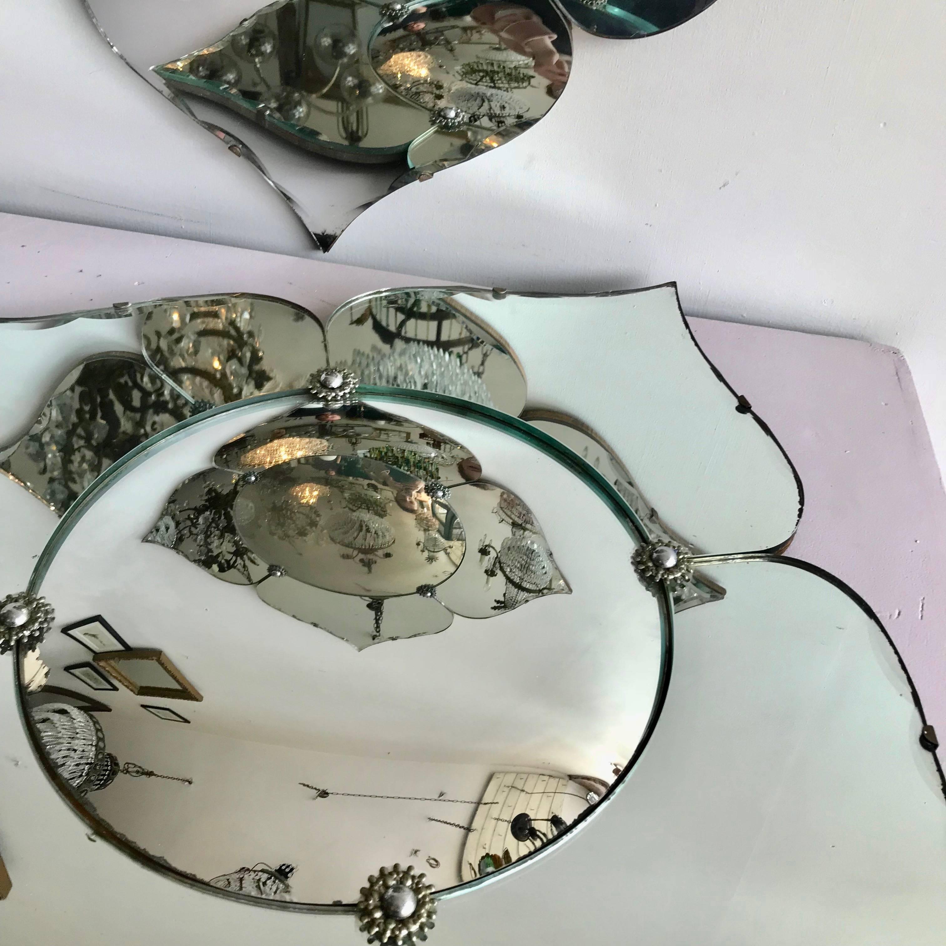 Pair of early 20th century Art Deco petal shaped frameless mirrors with convex centre mirrors each framed by four bevelled edge petals united by chromium flower heads. Slight damage and natural tarnishing to the mirror in places due to the age of