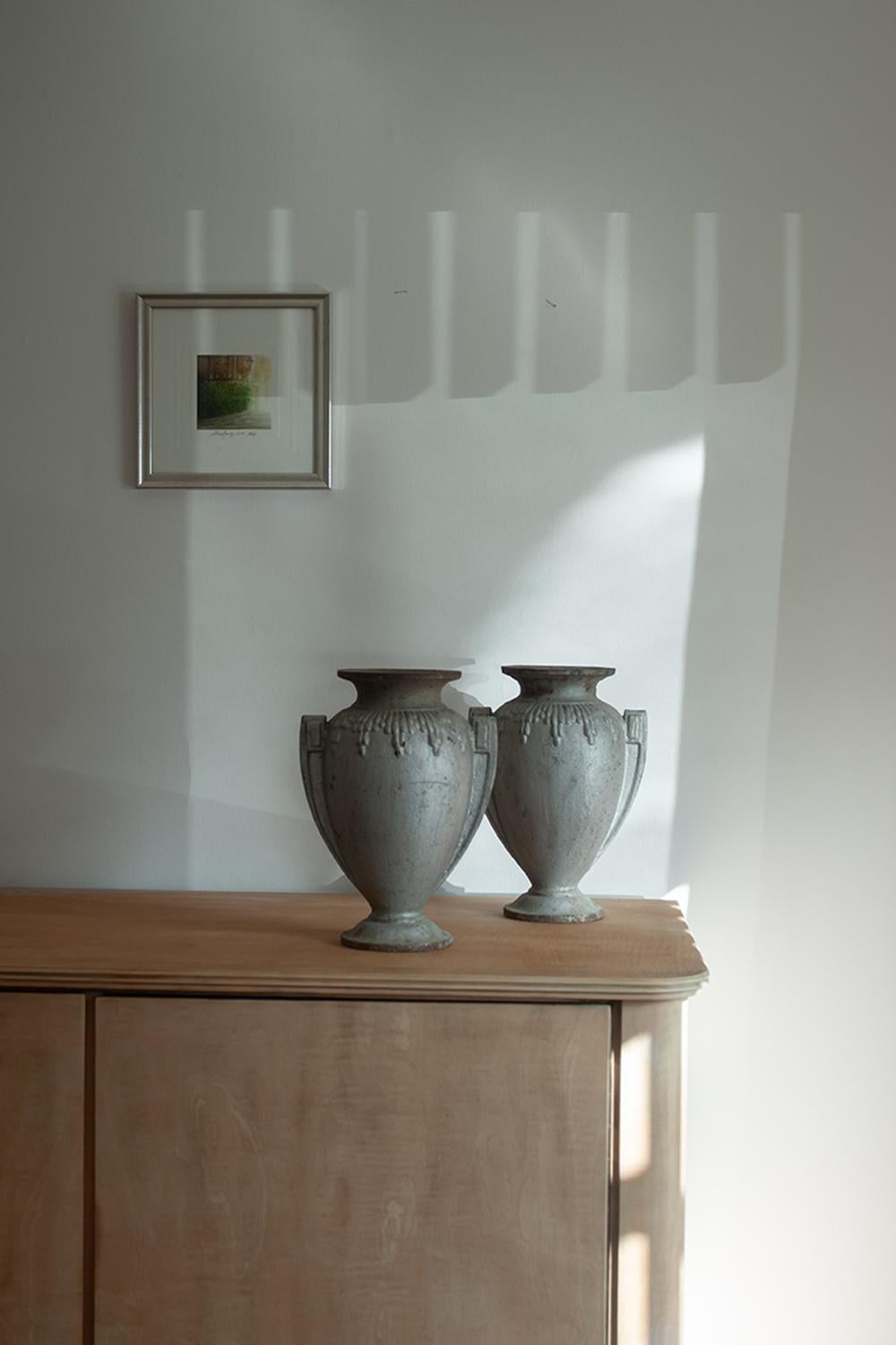 This pair of cast iron urns or vases are from the twentieth century. Sourced in the south of France, these stunning vases have a beautiful patina and uniquely cast shape. The vases show rust due to their age and outdoor use but are sure to add