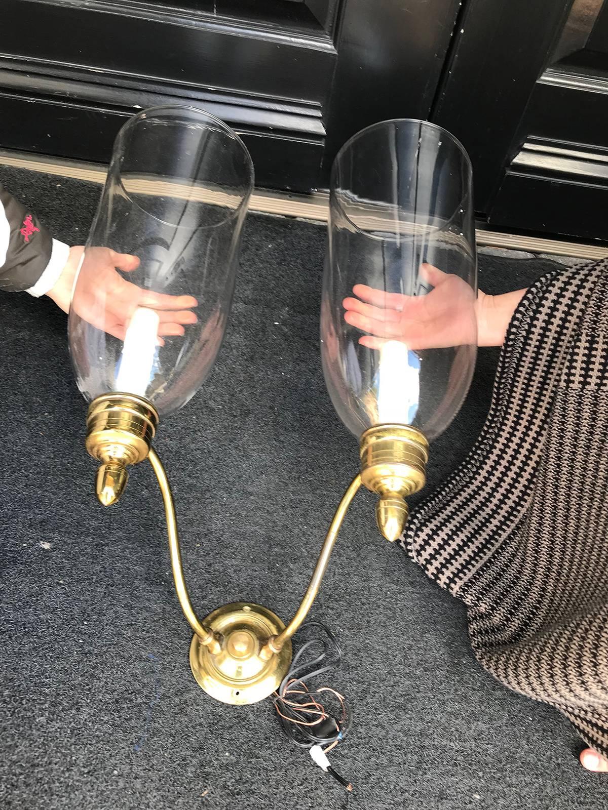 Pair of early 20th century brass, two-arm sconces with handblown hurricanes.