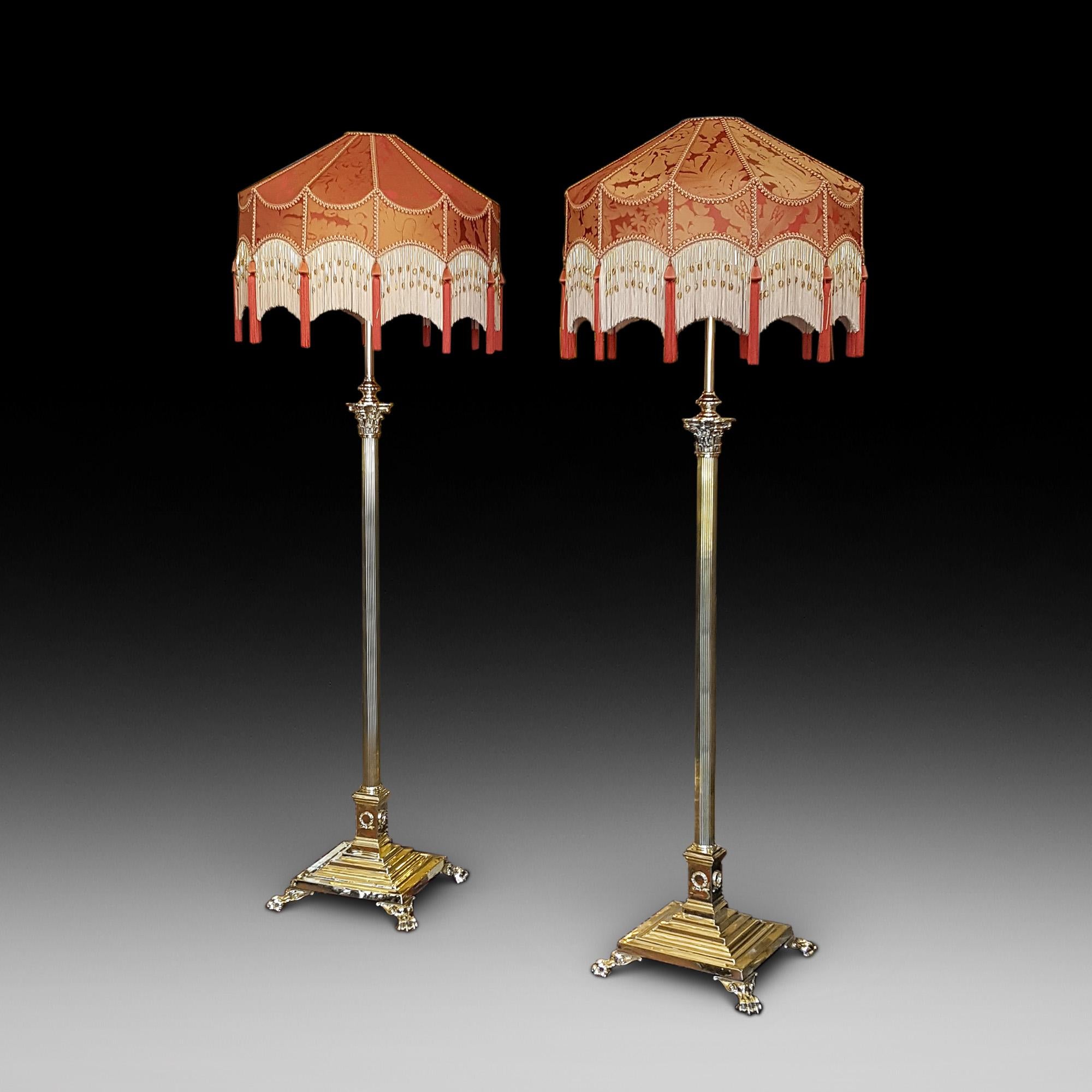 Pair of early 20th century neoclassical brass telescopic standard lamps, in the form of a Corinthian column, on platform base decorated with laurel wreaths with paw feet - The lampshade(s) are newly handmade silks by the same maker as provides the