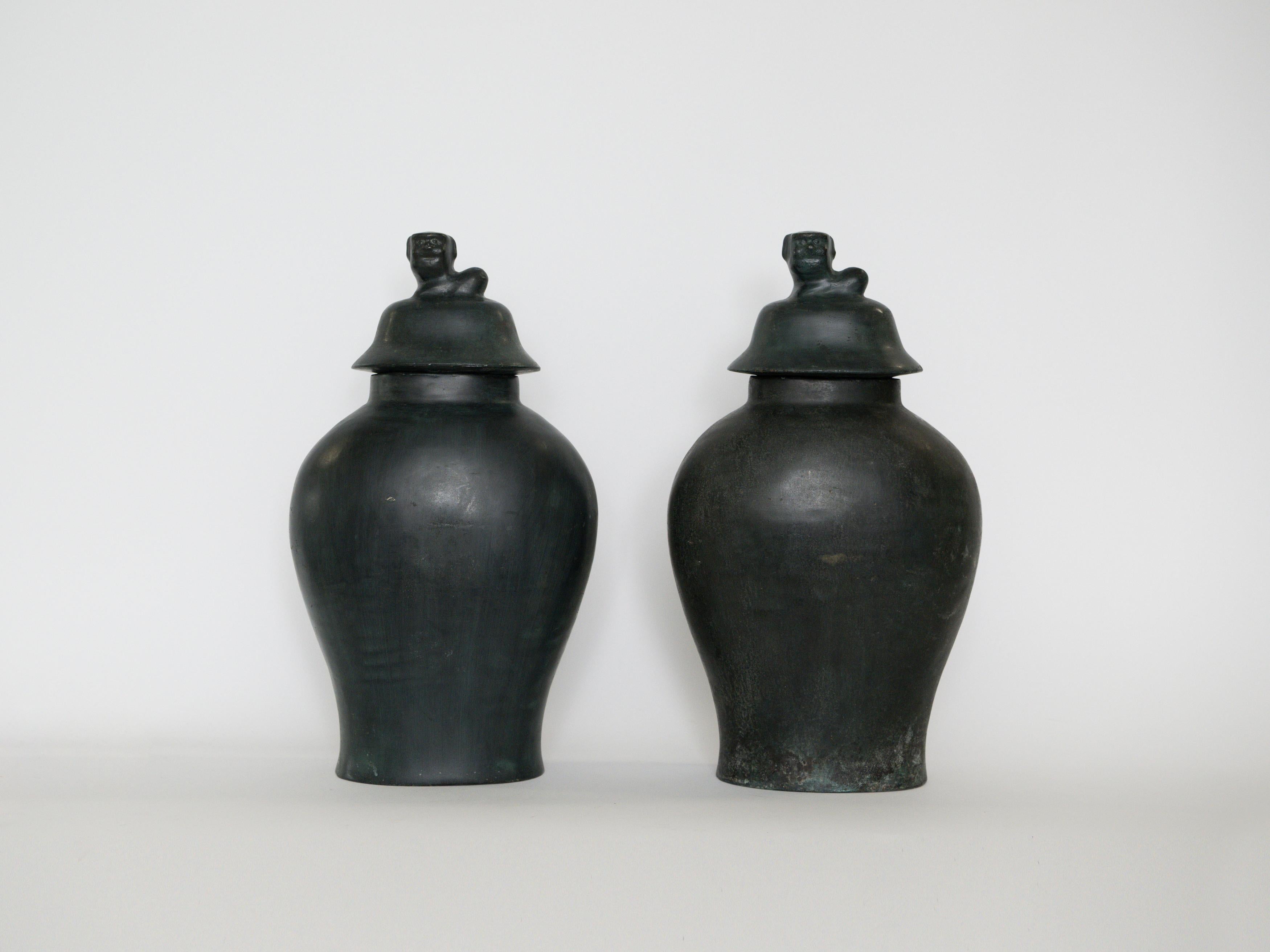These gorgeous hand-crafted urns have a complex, layered patinated with a dark matte finish.  Early 20th Century bronzes occasionally used stylized mythical beasts or sea creatures as finials.  The little creature on the lid is most often a Chinese