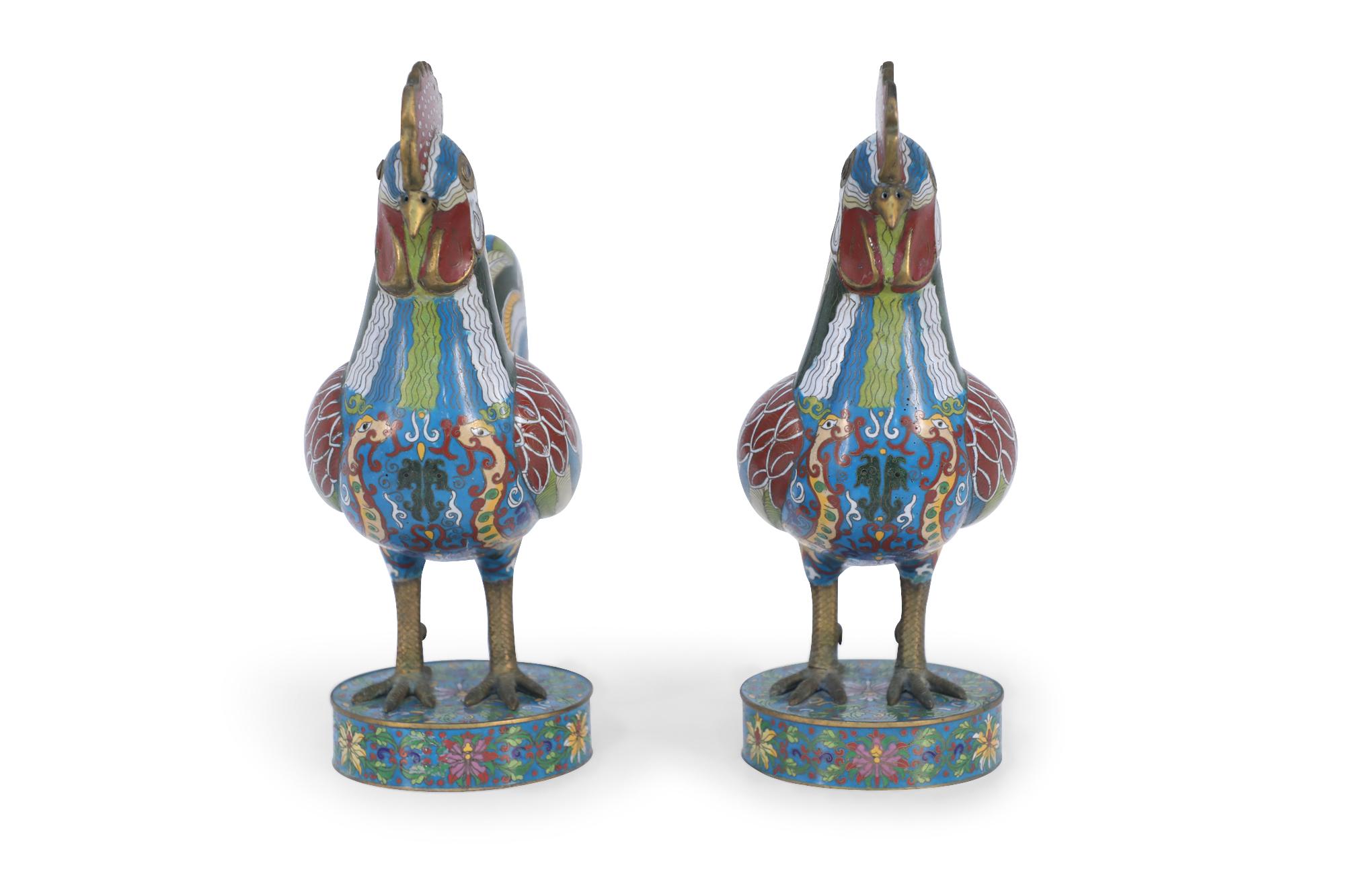Pair of early 20th century Chinese cloisonne rooster sculptures with red, white, blue, green, and yellow enamels standing on circular cloisonne bases with a floral border design.