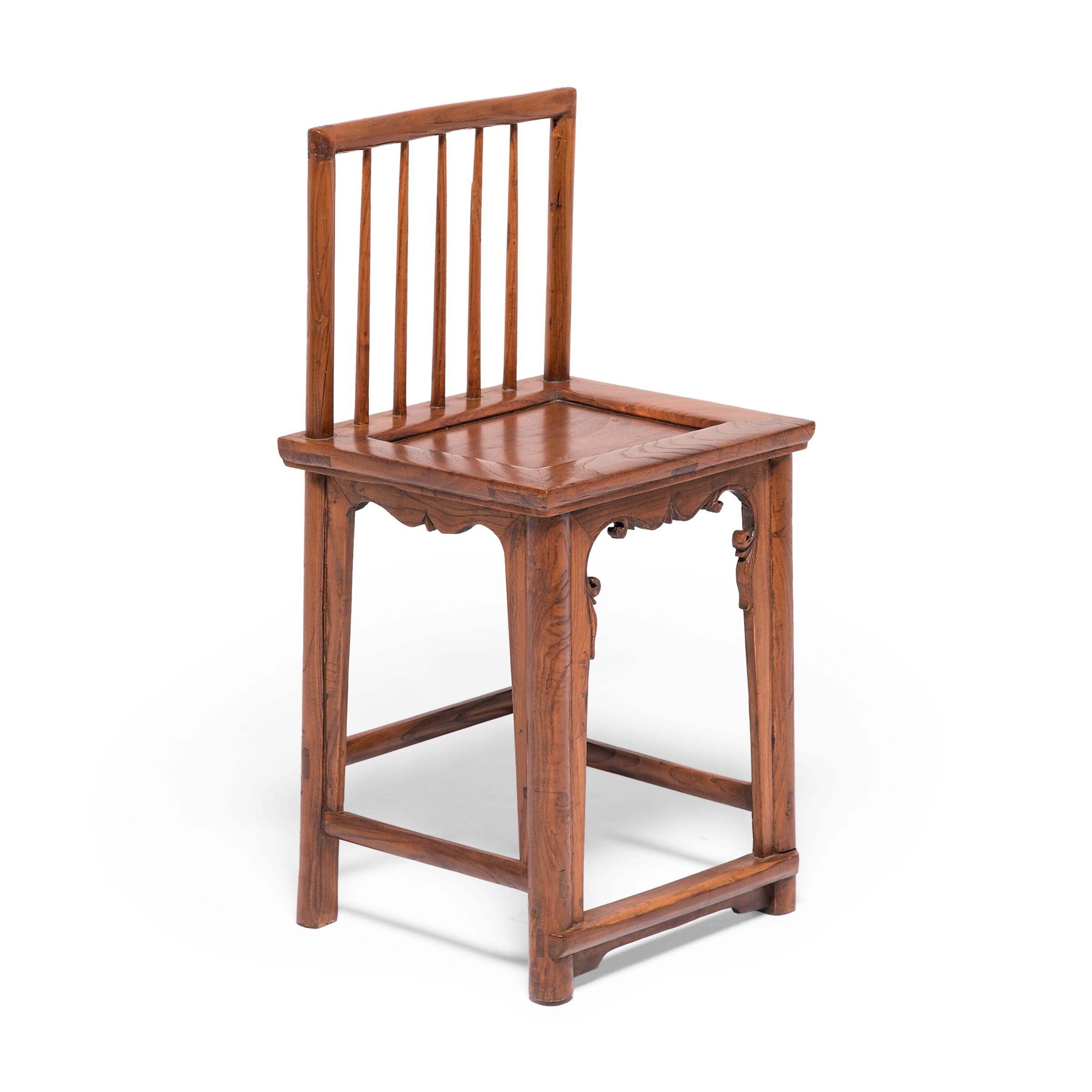 This pair of early 20th century walnut chairs owes its graceful design to the styles and techniques that emerged during the Ming dynasty, the golden age of Chinese furniture design. The clean lines of the spindleback form are interrupted by carved
