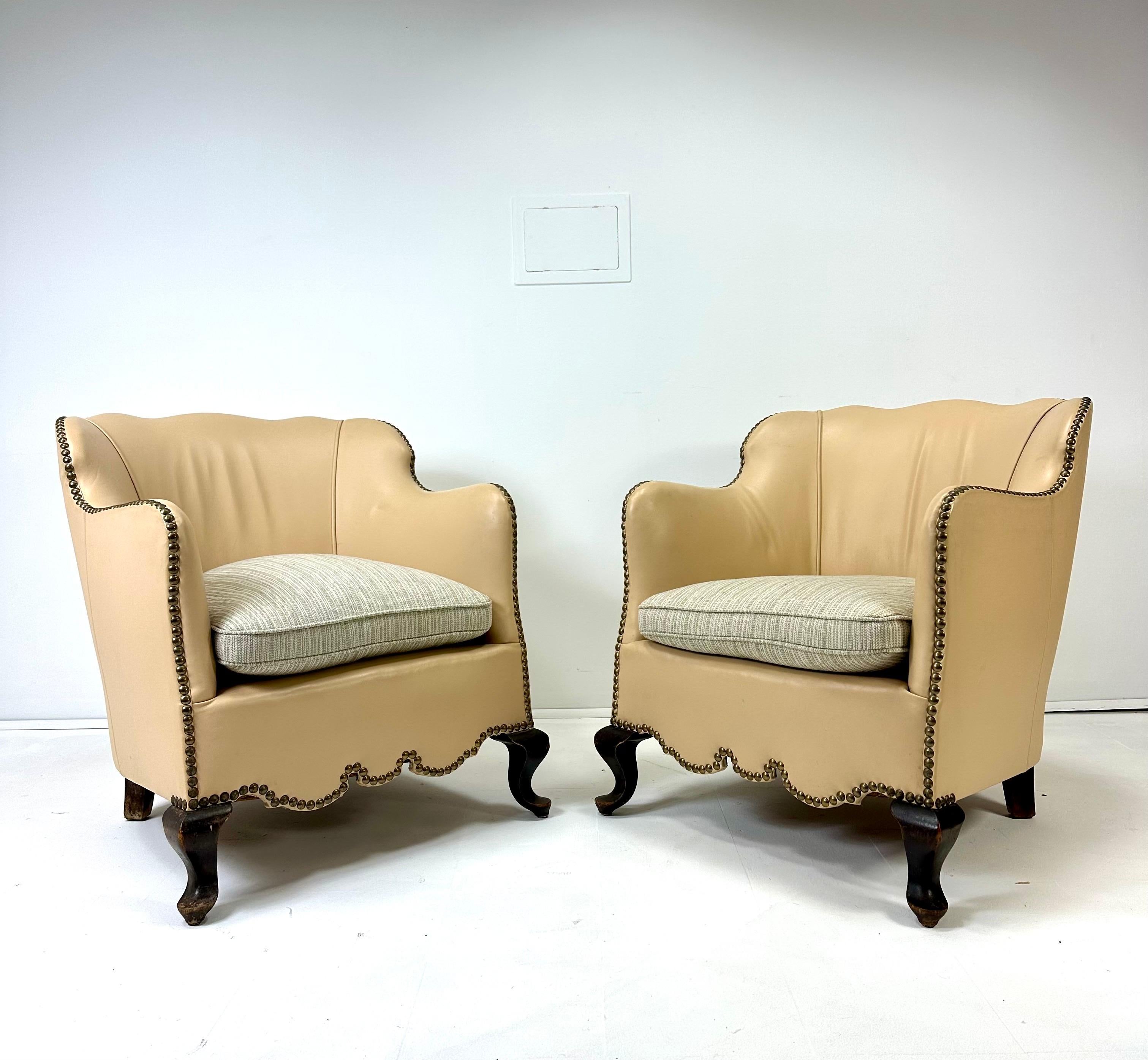 Paire de chaises longues danoises du début du XXe siècle. Revêtement en cuir avec détails en tête de clou. Coussin de siège mal fixé.