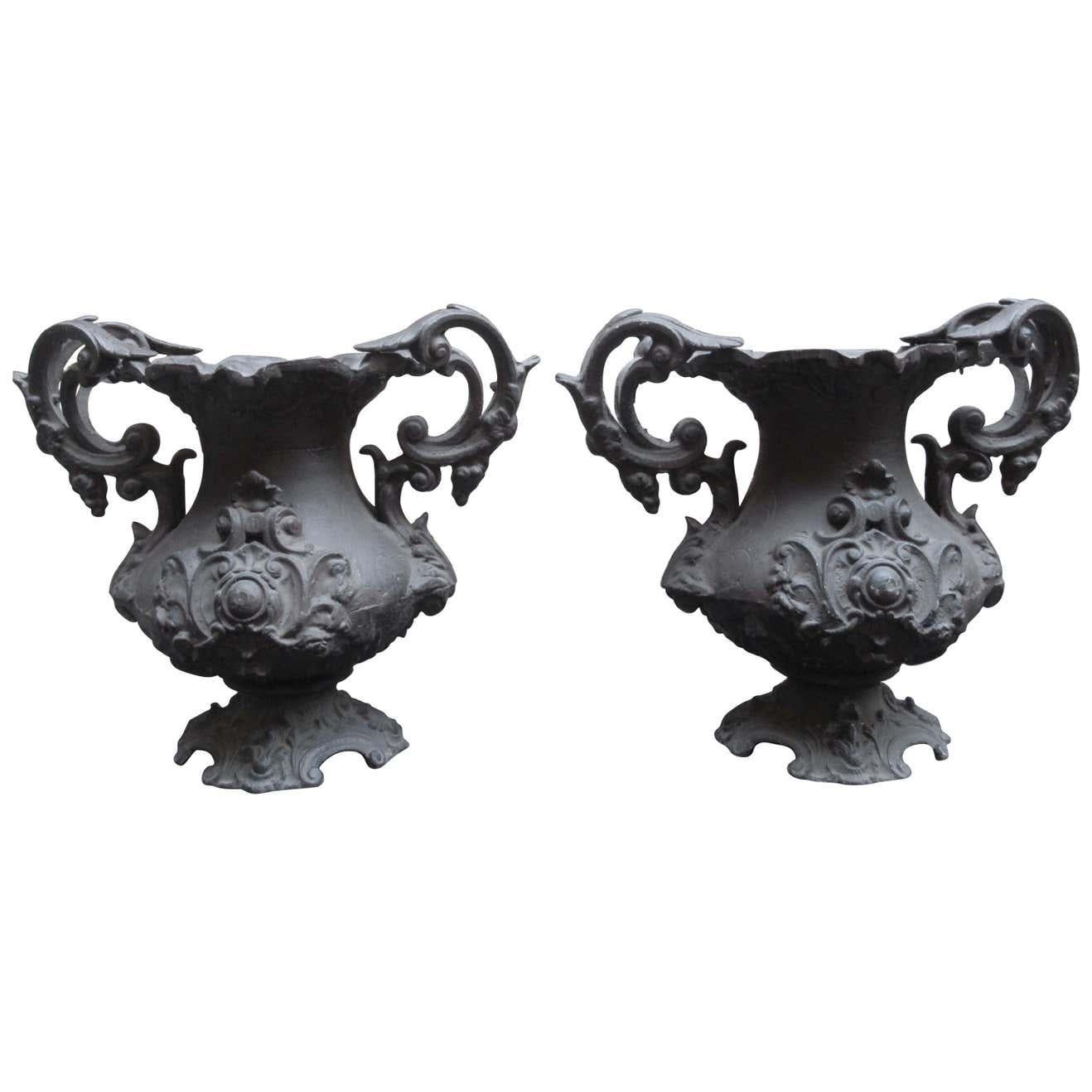 Pair of early 20th century cast iron urns with decorative foliate work and scroll handles. Beautiful shape and detail with a good patina for the age. Perfect for statement for your garden or entrance.