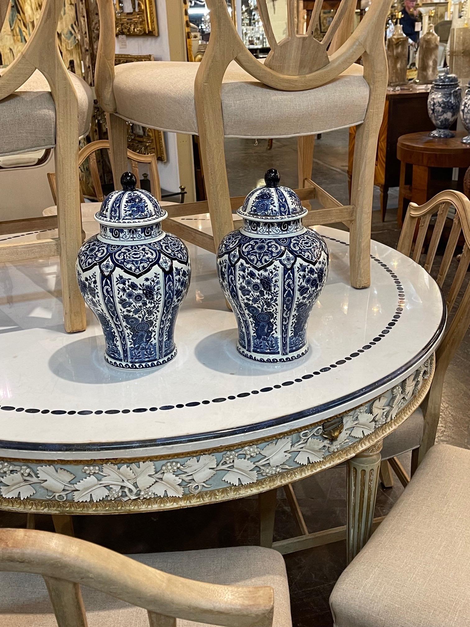 Lovely pair of early 20th century Delft blue and white ginger jars. Very pretty decorative floral designs. A fine accessory that makes a great gift!