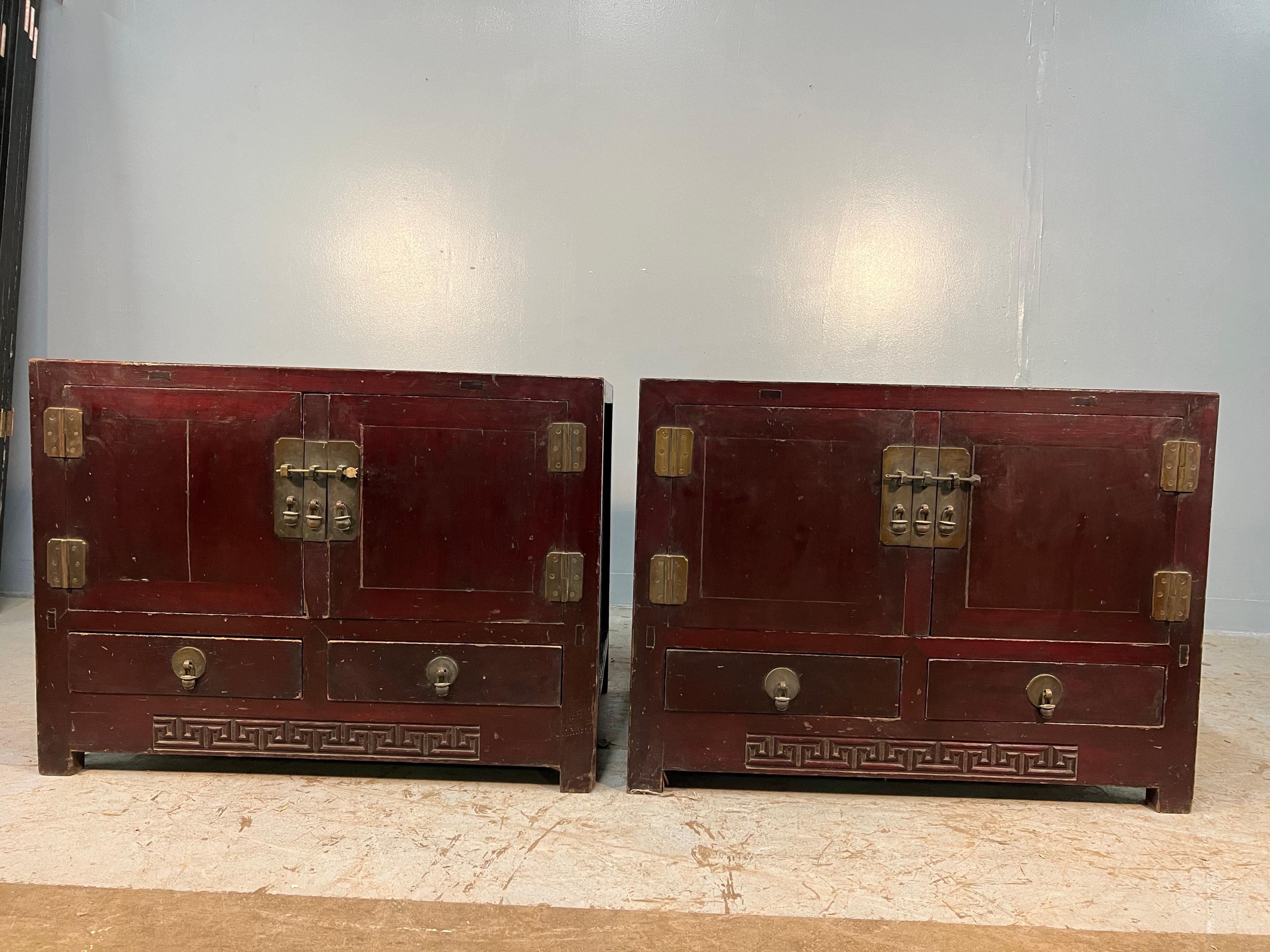 Ein Paar chinesische Ulmenholzschränke aus dem frühen 20. Jahrhundert in alter Lackierung. Dieses Schrankpaar ist ideal als Nachttisch oder als Beistelltisch neben dem Sofa. 
Sie bieten mit jeweils zwei Schubladen und zwei Türen reichlich