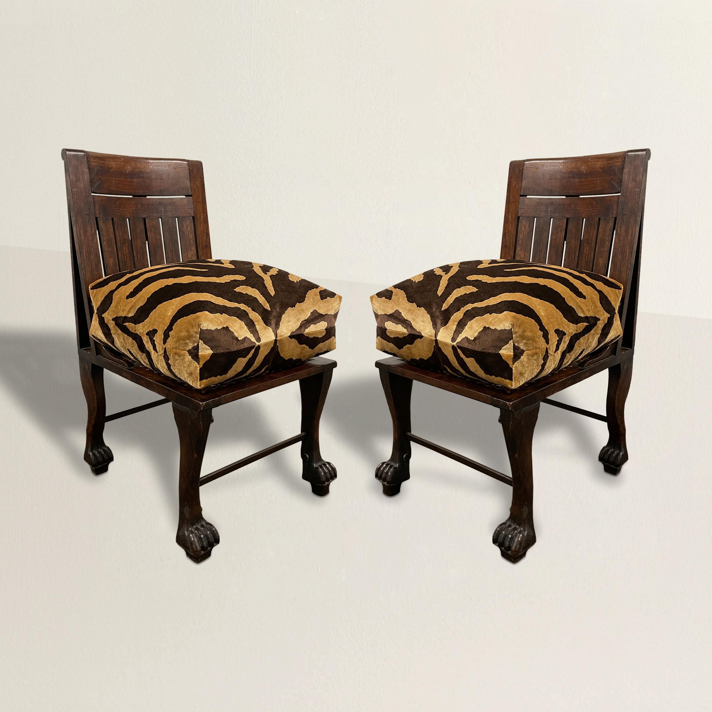 An incredibly rare pair of early 20th century English Egyptian Revival slipper chairs inspired by an Egyptian 18th Dynasty chair discovered in 1905. The frames are carved of walnut and feature legs carved to imitate the fore and hind legs of lions,