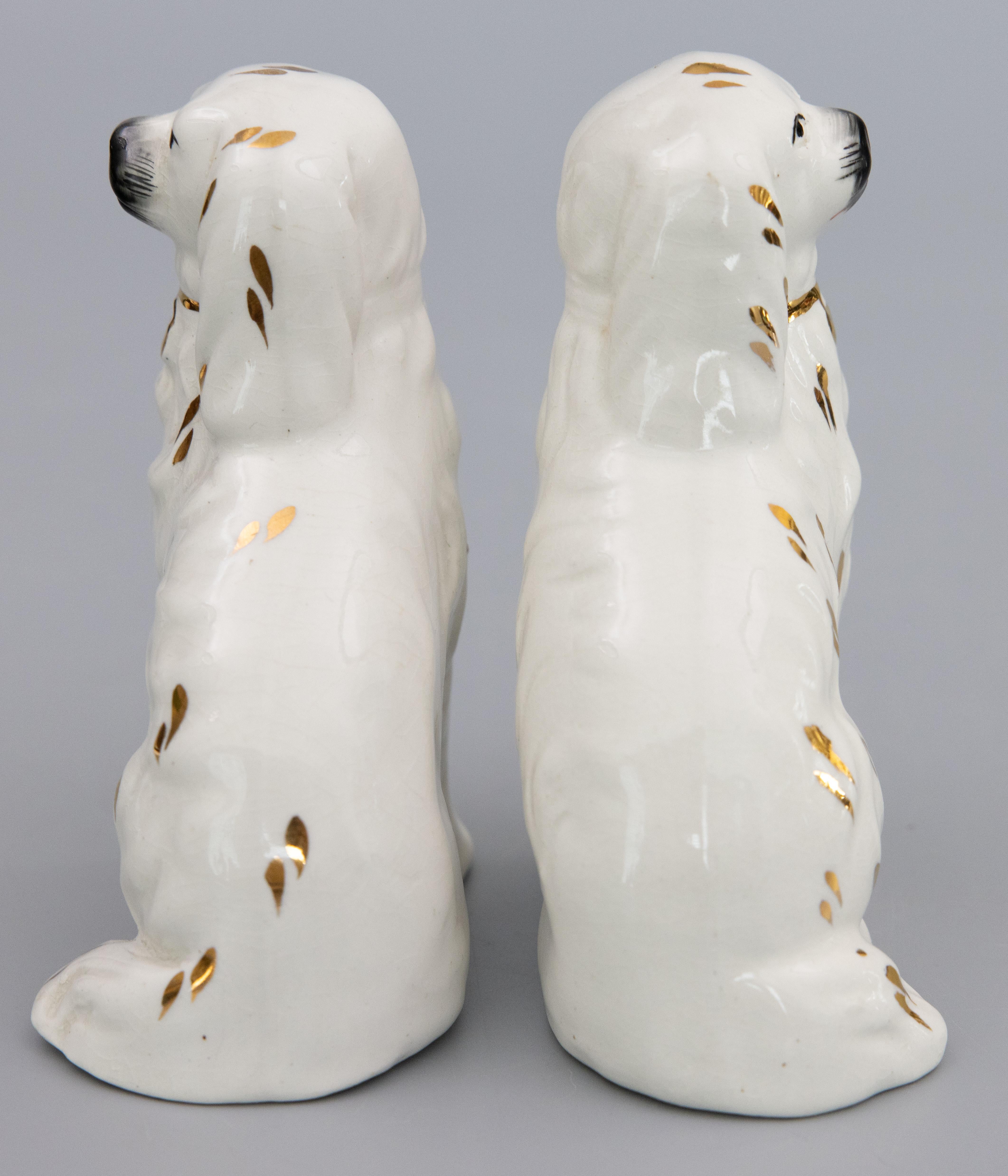 A wonderful pair of antique early 20th-Century English Staffordshire spaniel dogs with gilt accents. Maker's mark on reverse. These charming dogs are hand painted with beautiful details and the sweetest expressions. It's hard not to be smitten! They